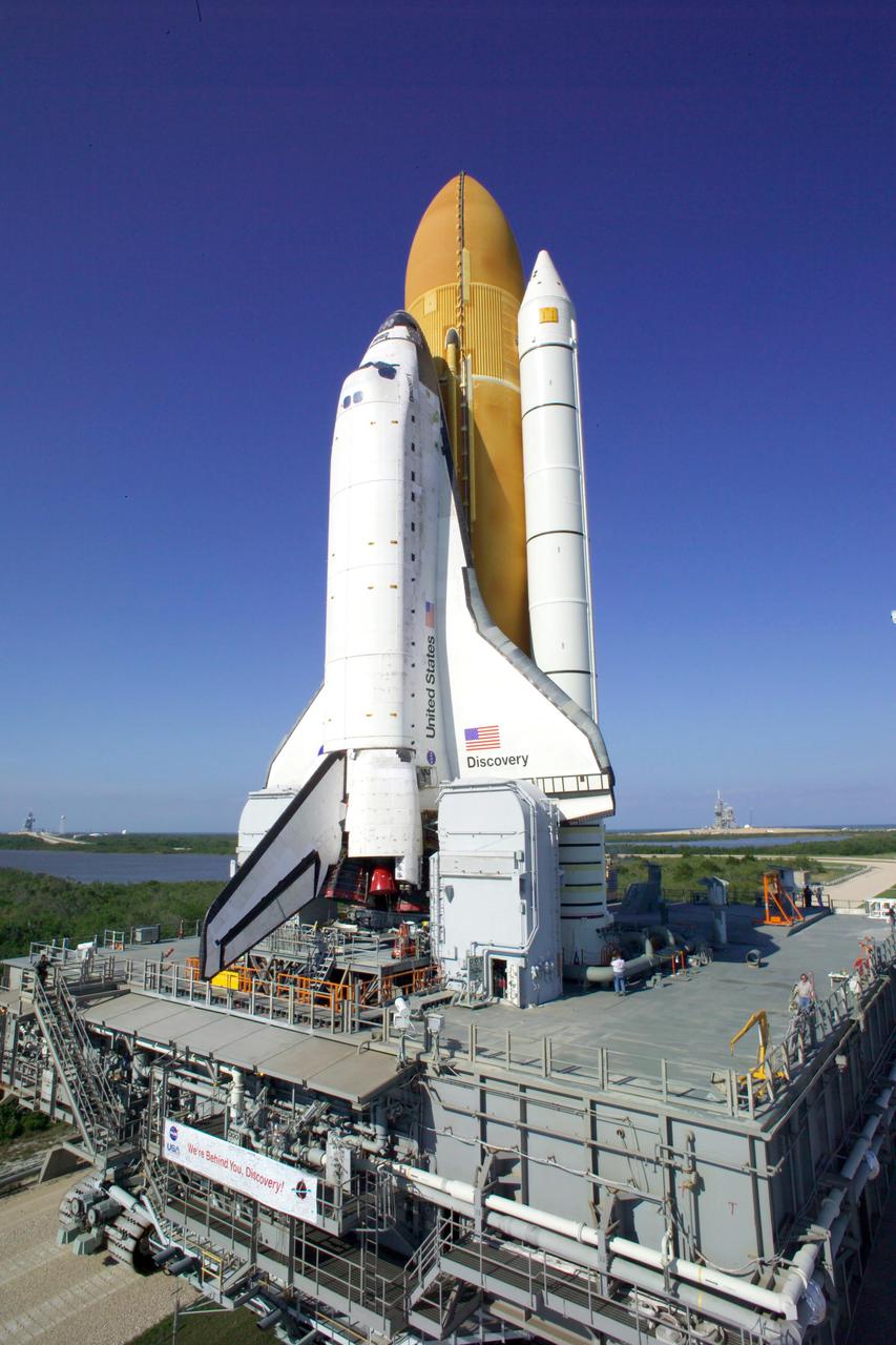 KENNEDY SPACE CENTER, FLA. -   At NASA’s Kennedy Space Center, Space Shuttle Discovery, atop the Mobile Launcher Platform (MLP), crawls toward Launch Complex 39B.  Barely visible on the horizon at right is Pad 39A. First motion out of the Vehicle Assembly Building occurred at 2:04 p.m. EDT. The rollout marks a major milestone in the Space Shuttle Program’s Return to Flight. The MLP is moved by the Crawler-Transporter underneath, which stands 20 feet high, 131 feet long and 114 feet wide.  It moves on eight tracks, each containing 57 shoes, or cleats, weighing one ton each.  Loaded with the Space Shuttle, the Crawler can move at a maximum speed of approximately 1 mile an hour. A leveling system in the Crawler keeps the Shuttle vertical while negotiating the 5 percent grade leading to the top of the launch pad.  Launch of Discovery on its Return to Flight mission, STS-114, is targeted for May 15 with a launch window that extends to June 3. During its 12-day mission, Discovery’s seven-person crew will test new hardware and techniques to improve Shuttle safety, as well as deliver supplies to the International Space Station.