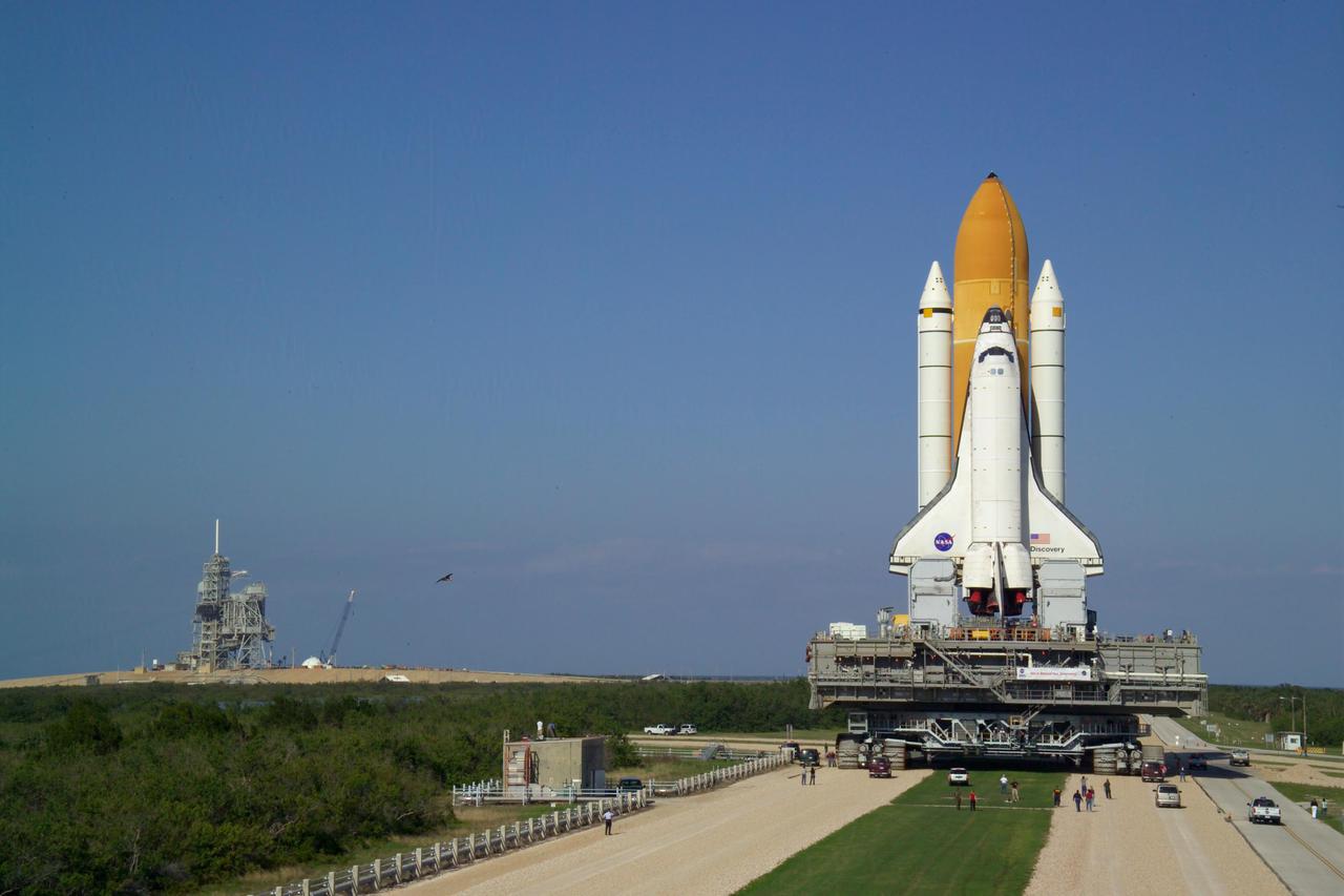 KENNEDY SPACE CENTER, FLA. -   Blue sky blends with the blue Atlantic Ocean as Space Shuttle Discovery, atop the Mobile Launcher Platform (MLP), crawls toward Launch Complex 39A, on its way to Pad 39B. First motion out of the Vehicle Assembly Building occurred at 2:04 p.m. EDT.  The rollout marks a major milestone in the Space Shuttle Program’s Return to Flight. The MLP is moved by the Crawler-Transporter underneath, which stands 20 feet high, 131 feet long and 114 feet wide.  It moves on eight tracks, each containing 57 shoes, or cleats, weighing one ton each.  Loaded with the Space Shuttle, the Crawler can move at a maximum speed of approximately 1 mile an hour. A leveling system in the Crawler keeps the Shuttle vertical while negotiating the 5 percent grade leading to the top of the launch pad.  Launch of Discovery on its Return to Flight mission, STS-114, is targeted for May 15 with a launch window that extends to June 3. During its 12-day mission, Discovery’s seven-person crew will test new hardware and techniques to improve Shuttle safety, as well as deliver supplies to the International Space Station.