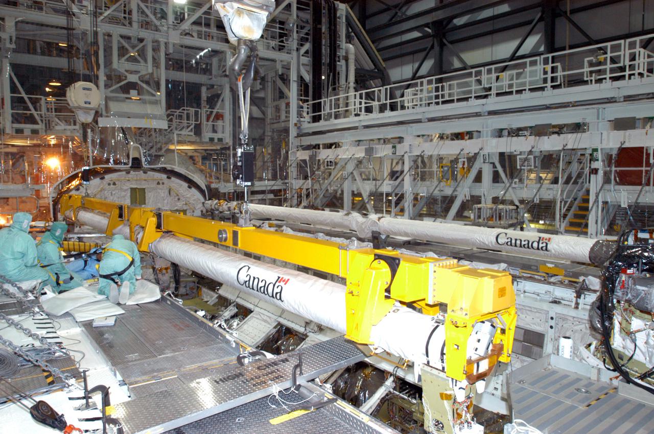 KENNEDY SPACE CENTER, FLA. - In the Orbiter Processing Facility bay 1 at NASA’s Kennedy Space Center, workers are installing the Orbital Boom Sensor System (foreground) in Atlantis’ payload bay.  The 50-foot-long OBSS attaches to the Remote Manipulator System (background), or Shuttle robotic arm, and is one of the new safety measures for Return to Flight.  It equips the orbiter with cameras and laser systems to inspect the Shuttle’s Thermal Protection System while in space.  Mission STS-121 is targeted for launch in July.