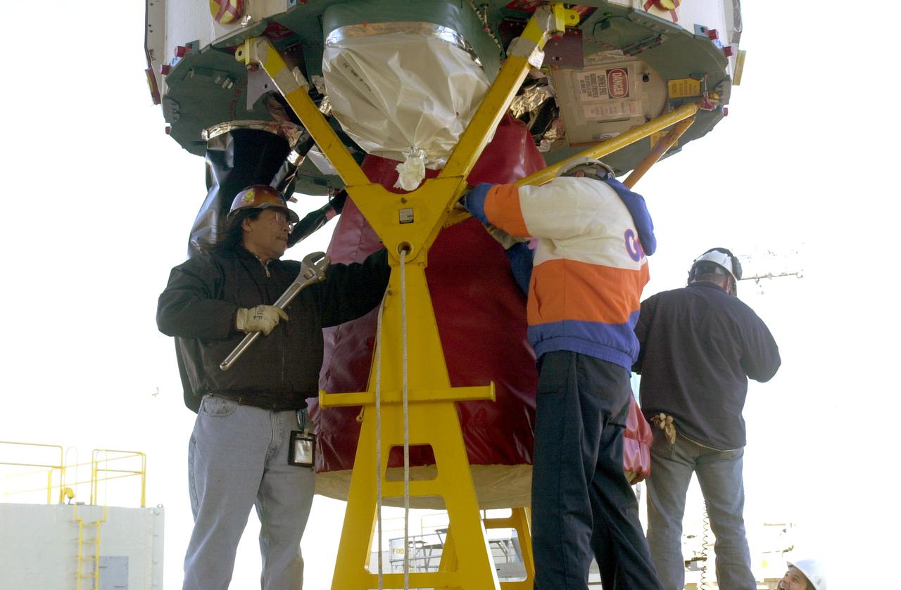 VANDENBERG AIR FORCE BASE, CALIF. - Workers on Space Launch Complex 2 at Vandenberg Air Force Base in California secure the engine on the first stage of a Boeing Delta 2 rocket.  The rocket will be lifted up the launch service tower.  The Delta 2 is the launch vehicle for the National Oceanic and Atmospheric Administration (NOAA-N) spacecraft.The NOAA-N satellite will be placed into a polar orbit aboard a Boeing Delta 2 rocket.  The spacecraft will continue to provide a polar-orbiting platform to support (1) environmental monitoring instruments for imaging and measuring the Earth's atmosphere, its surface, and cloud cover, including Earth radiation, atmospheric ozone, aerosol distribution, sea surface temperature, and vertical temperature and water profiles in the troposphere and stratosphere; (2) measurement of proton and electron flux at orbit altitude; (3) data collection from remote platforms; and (4) the Search and Rescue Satellite-Aided Tracking (SARSAT) system.  Additionally, NOAA-N is the fourth in the series of support dedicated microwave instruments for the generation of temperature, moisture, surface, and hydrological products in cloudy regions where visible and infrared (IR) instruments have decreased capability.  Launch is currently scheduled for no earlier than May 11, 2005.