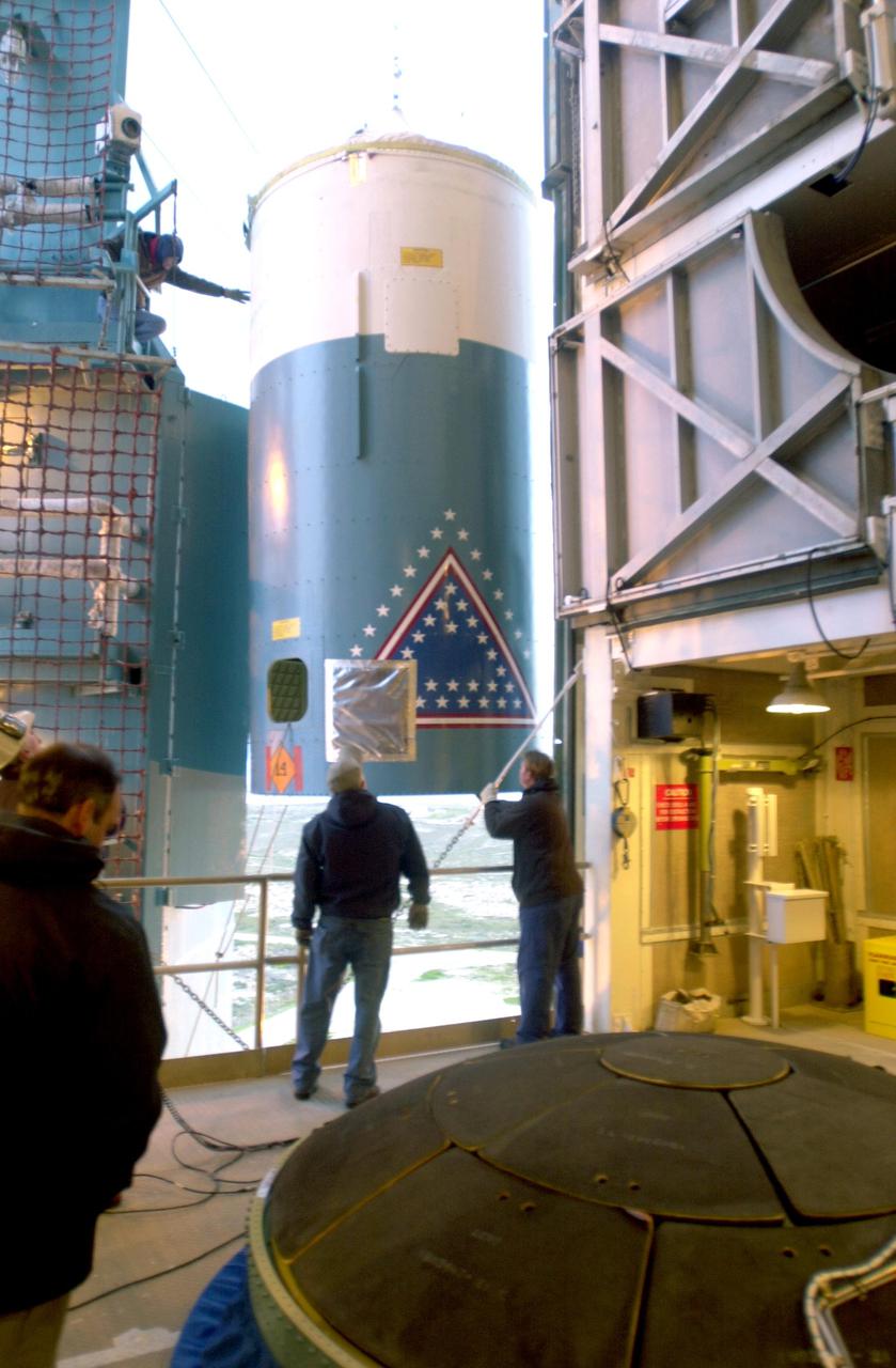 VANDENBERG AIR FORCE BASE, CALIF. - The interstage of a Boeing Delta 2 rocket is lifted to an upper level on the launch service tower on Space Launch Complex 2 at Vandenberg Air Force Base in California.  It will be mated with the first stage in the launch service tower.   In the foreground is the interstage adapter.  The Delta 2 is the launch vehicle for the National Oceanic and Atmospheric Administration (NOAA-N) spacecraft. The NOAA-N satellite will be placed into a polar orbit aboard a Boeing Delta 2 rocket.  The spacecraft will continue to provide a polar-orbiting platform to support (1) environmental monitoring instruments for imaging and measuring the Earth's atmosphere, its surface, and cloud cover, including Earth radiation, atmospheric ozone, aerosol distribution, sea surface temperature, and vertical temperature and water profiles in the troposphere and stratosphere; (2) measurement of proton and electron flux at orbit altitude; (3) data collection from remote platforms; and (4) the Search and Rescue Satellite-Aided Tracking (SARSAT) system.  Additionally, NOAA-N is the fourth in the series of support dedicated microwave instruments for the generation of temperature, moisture, surface, and hydrological products in cloudy regions where visible and infrared (IR) instruments have decreased capability.  Launch is currently scheduled for no earlier than May 11, 2005.
