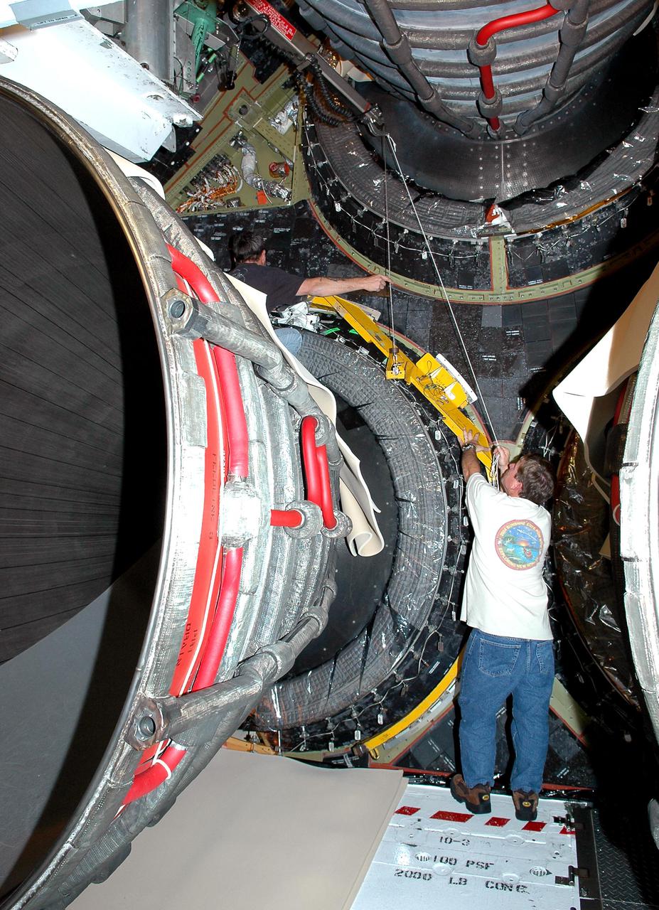 KENNEDY SPACE CENTER, FLA. - Dave Fentris (upper left) and Gary Austin , aft mechanical technicians with United Space Alliance, are attaching dome heat shields to Space Shuttle Main Engines (SSME) on the orbiter Atlantis in Orbiter Processing Facility bay 1. The shields provide protection for the orbiter against the high temperatures generated by an SSME. The liquid hydrogen fuel is - 423 degrees Fahrenheit, the second coldest liquid on Earth. When the hydrogen is burned with liquid oxygen, the temperature in the engine's combustion chamber reaches +6000 degrees Fahrenheit - that’s higher than the boiling point of iron. Each SSME is controlled by its own computer, which checks the health of the engines 50 times per second during countdown and ascent. The controller can shut an engine down if it detects a problem. Atlantis is scheduled to launch in July on mission STS-121.
