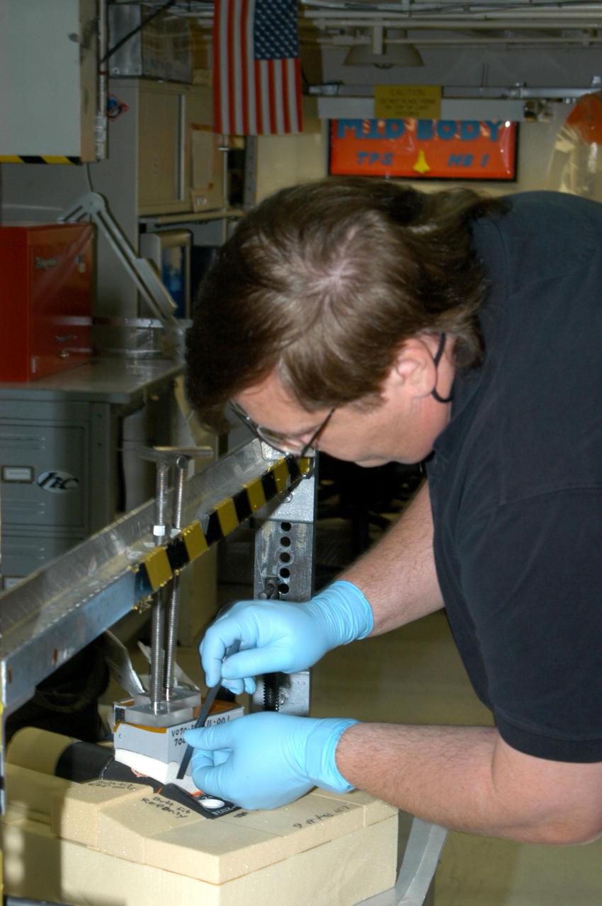 KENNEDY SPACE CENTER, FLA.  -  In the Orbiter Processing Facility bay 1, United Space Alliance technician George Arnett works on tile bonding for the orbiter Atlantis.  The orbiter is scheduled to fly on Return to Flight mission STS-121 in July.  STS-121 is a Return to Flight Utilities and Logistics Flight (ULF-2) to the International Space Station.
