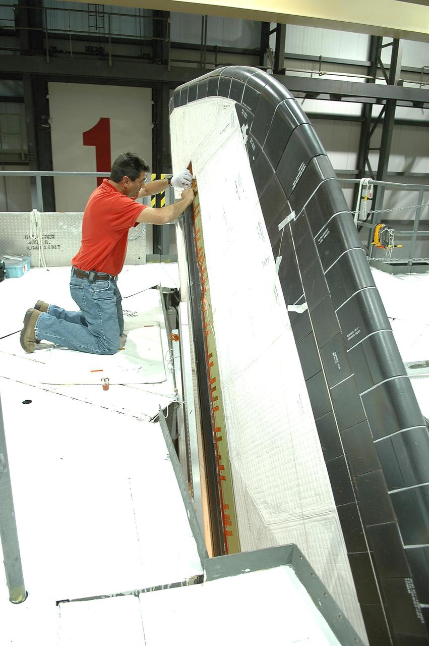 KENNEDY SPACE CENTER, FLA.  - In the Orbiter Processing Facility at NASA’s Kennedy Space Center, United Space Alliance tile technician Jimmy Carter works on instrument wire spot bonding on Atlantis’ vertical tail_rudder speed brake.  Atlantis is being processed for launch on the second Return to Flight mission, STS-121, which is scheduled to fly in July.