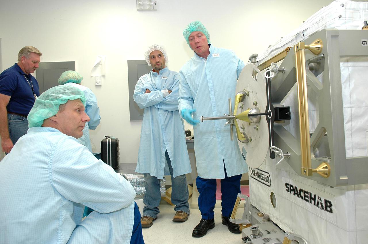 KENNEDY SPACE CENTER, FLA. - Mission Specialist Piers J. Sellers, Ph.D., (kneeling, left) and Michael E. Fossum (right) look at the adjustable grapple bar on the SPACEHAB Oceaneering Enhanced Deployable box. The astronauts of the second Return to Flight mission, STS-121, were at the SPACEHAB facility in Cape Canaveral to participate in the Crew Equipment Interface Test (CEIT). This test allows the astronauts to become familiar with equipment they will be using on their upcoming mission. STS-121 is scheduled to launch in July aboard Space Shuttle Atlantis.