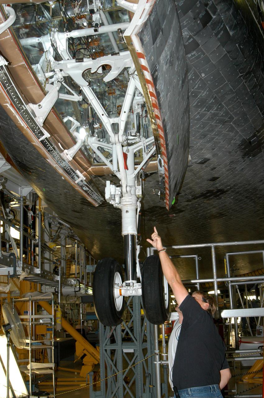 KENNEDY SPACE CENTER, FLA. - In the Orbiter Processing Facility at NASA’s Kennedy Space Center, United Space Alliance technicians Terry Williams (left) and Ron Delaney examine Space Shuttle Atlantis before retracting the nose landing gear. Compression measurements will be taken of the newly installed nose landing gear thermal barrier seal with the gear in position in its wheel well and the landing gear doors closed. Atlantis is being processed for launch on the second Return to Flight mission, STS-121, which is scheduled to fly in July.