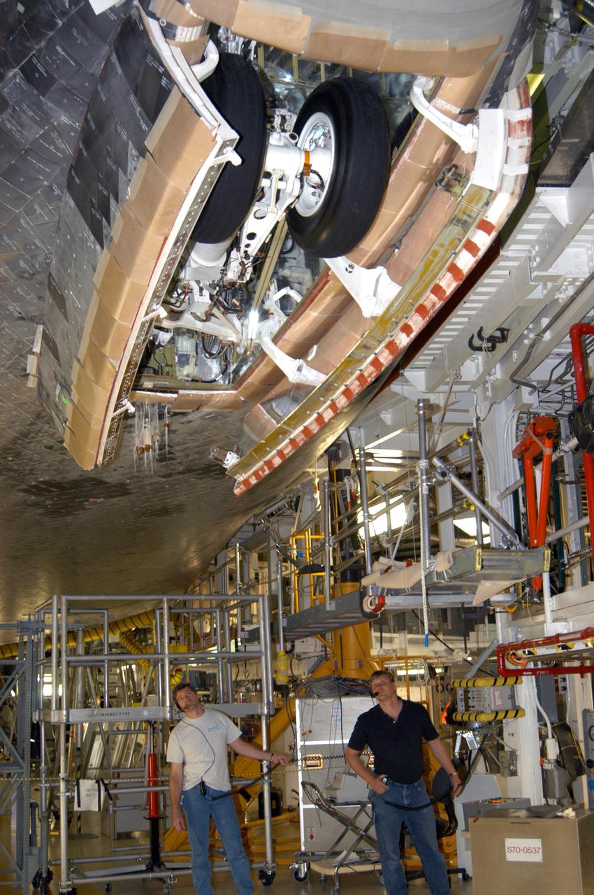 KENNEDY SPACE CENTER, FLA. - In the Orbiter Processing Facility at NASA’s Kennedy Space Center, United Space Alliance technicians Terry Williams (left) and Ron Delaney retract the nose landing gear on Space Shuttle Atlantis. Compression measurements will be taken of the newly installed nose landing gear thermal barrier seal with the gear in position in its wheel well and the landing gear doors closed.  Atlantis is being processed for launch on the second Return to Flight mission, STS-121, which is scheduled to fly in July.