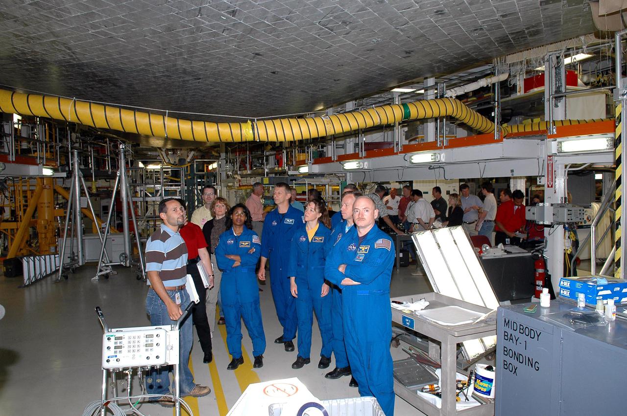 KENNEDY SPACE CENTER, FLA. - In the Orbiter Processing Facility, the STS-121 crew receives a briefing and up-close look beneath Space Shuttle Atlantis, the orbiter that will take them into space. From left, in the blue flight suits, are Mission Specialists Stephanie D. Wilson, Piers J. Sellers, and Lisa M. Nowak; Commander Steven W. Lindsey and Pilot Mark E. Kelly. The astronauts of the second Return to Flight mission, STS-121, are at Kennedy Space Center to participate in the Crew Equipment Interface Test (CEIT). During CEIT, the crew has an opportunity to get a hands-on look at the orbiter and equipment they will be working with on their mission. Mission STS-121 is scheduled to launch in July.
