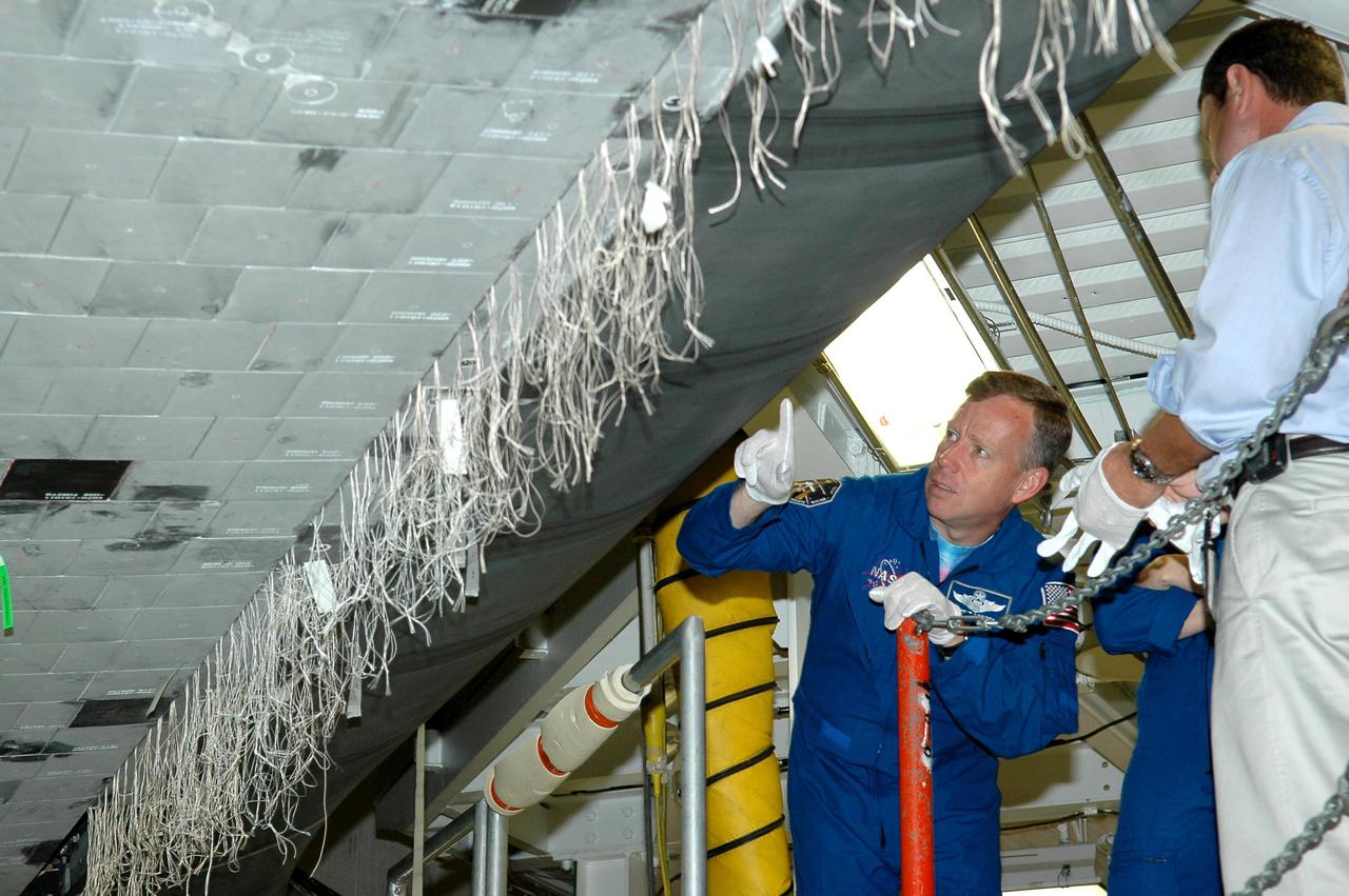 KENNEDY SPACE CENTER, FLA. - In the Orbiter Processing Facility, STS-121 Commander Steven W. Lindsey (left) receives a briefing and up-close look at the wing leading edge of Space Shuttle Atlantis, the orbiter that will take his crew into space. The leading edge of each of the orbiters’ wings has 22 Reinforced Carbon-Carbon panels, made entirely of carbon composite material. The molded components are approximately 0.25-inch to 0.5-inch thick. Lindsey and the other STS-121 crew members are at Kennedy Space Center to participate in the Crew Equipment Interface Test (CEIT). During CEIT, the crew has an opportunity to get a hands-on look at the orbiter and equipment they will be working with on their mission. Mission STS-121 is scheduled to launch in July.