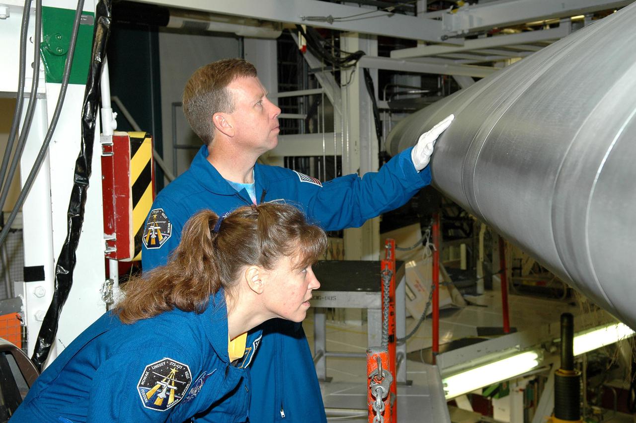 KENNEDY SPACE CENTER, FLA. - In the Orbiter Processing Facility, STS-121 Commander Steven W. Lindsey and Mission Specialist Lisa M. Nowak examine the wing leading edge of Space Shuttle Atlantis, the orbiter that will take them into space. The leading edge of each of the orbiters’ wings has 22 Reinforced Carbon-Carbon panels, made entirely of carbon composite material. The molded components are approximately 0.25-inch to 0.5-inch thick. Lindsey and the other STS-121 crew members are at Kennedy Space Center to participate in the Crew Equipment Interface Test (CEIT). During CEIT, the crew has an opportunity to get a hands-on look at the orbiter and equipment they will be working with on their mission. Mission STS-121 is scheduled to launch in July.