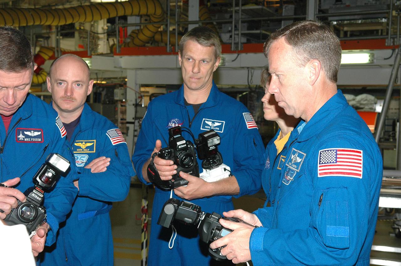 KENNEDY SPACE CENTER, FLA. - In the Orbiter Processing Facility, the STS-121 crew receives a briefing and up-close look at the handheld cameras they will carry into space. From left are Mission Specialist Michael E. Fossum, Pilot Mark E. Kelly, Mission Specialists Piers J. Sellers and Lisa M. Nowak, and Commander Steven W. Lindsey. The astronauts of the second Return to Flight mission, STS-121, are at Kennedy Space Center to participate in the Crew Equipment Interface Test (CEIT). During CEIT, the crew has an opportunity to get a hands-on look at the orbiter and equipment they will be working with on their mission. Mission STS-121 is scheduled to launch in July.