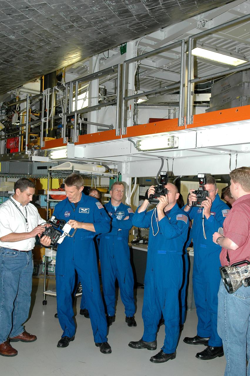 KENNEDY SPACE CENTER, FLA. - In the Orbiter Processing Facility, the STS-121 crew receives a briefing and up-close look beneath Space Shuttle Atlantis at the handheld cameras they will carry into space. From left, in the blue flight suits, are Mission Specialist Piers J. Sellers, Commander Steven W. Lindsey,  Pilot Mark E. Kelly and Mission Specialist Michael E. Fossum. The astronauts of the second Return to Flight mission, STS-121, are at Kennedy Space Center to participate in the Crew Equipment Interface Test (CEIT). During CEIT, the crew has an opportunity to get a hands-on look at the orbiter and equipment they will be working with on their mission. Mission STS-121 is scheduled to launch in July.