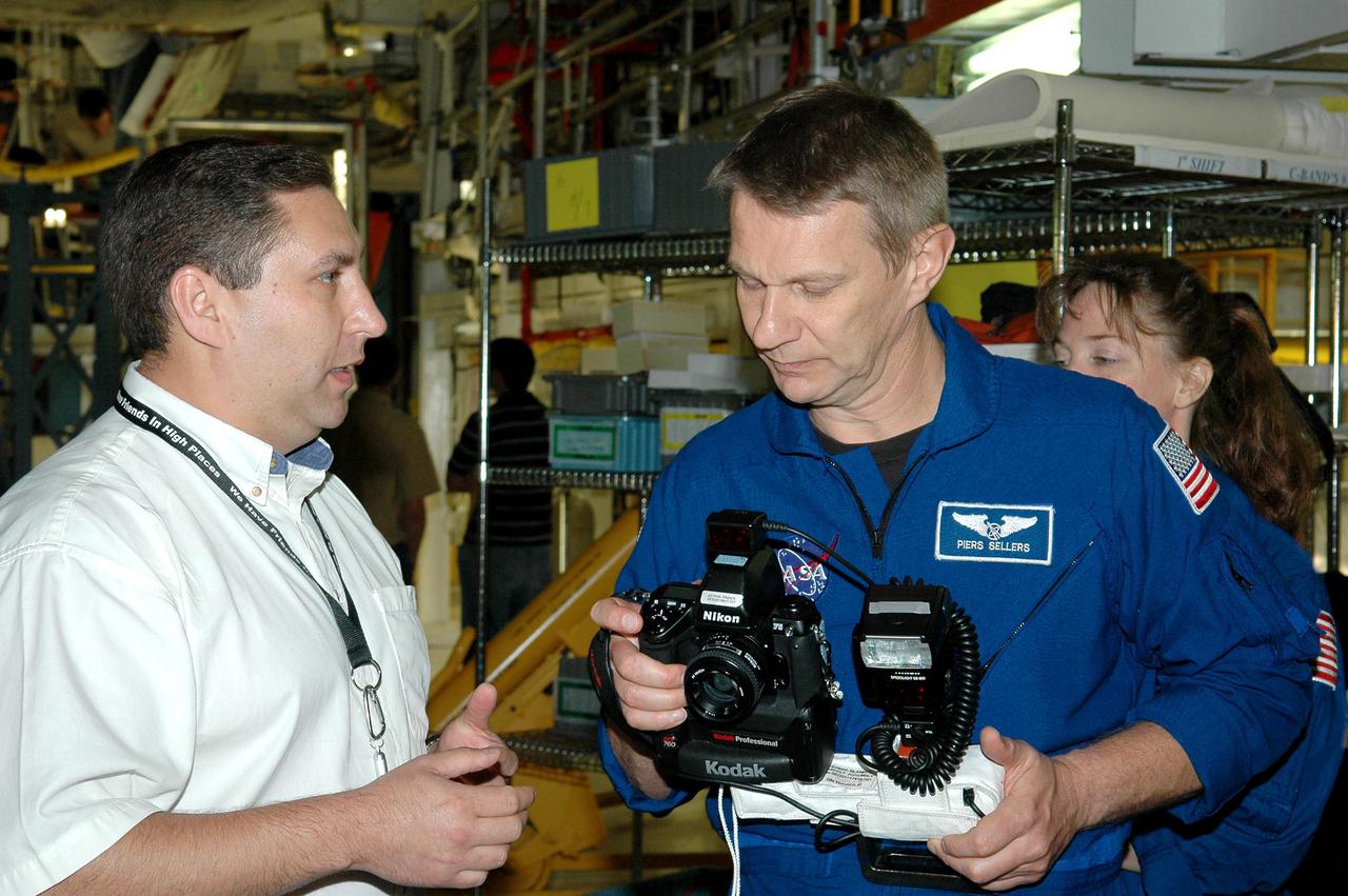KENNEDY SPACE CENTER, FLA. - In the Orbiter Processing Facility, the STS-121 crew receives a briefing and up-close look at the handheld cameras they will carry into space. From left, in the blue flight suits, are Mission Specialists Piers J. Sellers and Lisa M. Nowak. The astronauts of the second Return to Flight mission, STS-121, are at Kennedy Space Center to participate in the Crew Equipment Interface Test (CEIT). During CEIT, the crew has an opportunity to get a hands-on look at the orbiter and equipment they will be working with on their mission. Mission STS-121 is scheduled to launch in July.