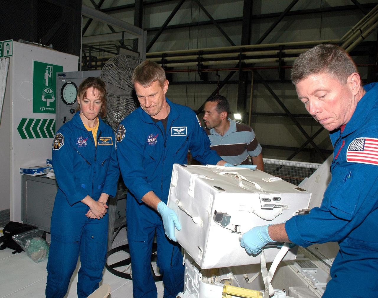 KENNEDY SPACE CENTER, FLA. - In the Orbiter Processing Facility at NASA’s Kennedy Space Center, astronauts of the second Return to Flight mission, STS-121, unload the Tile Repair Kit for a closer look at hardware they will be working with on the mission. Crew members seen in this photo are, left to right, Mission Specialists Lisa Nowak, Piers J. Sellers and Michael E. Fossum. The crew is at KSC to participate in the Crew Equipment Interface Test (CEIT). During CEIT, the crew has an opportunity to get a hands-on look at the orbiter and equipment they will be working with on their missions. Mission STS-121 is scheduled to launch aboard Atlantis in July.