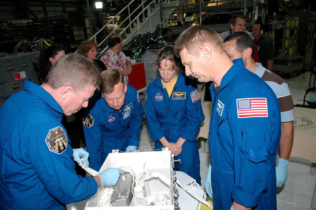 KENNEDY SPACE CENTER, FLA. - In the Orbiter Processing Facility at NASA’s Kennedy Space Center, astronauts of the second Return to Flight mission, STS-121, practice using the Tile Repair Kit. Crew members seen in this photo are, left to right, Mission Specialist Michael E. Fossum, Commander Steven W. Lindsey, and Mission Specialists Lisa Nowak and Piers J. Sellers. The crew is at KSC to participate in the Crew Equipment Interface Test (CEIT). During CEIT, the crew has an opportunity to get a hands-on look at the orbiter and equipment they will be working with on their missions. Mission STS-121 is scheduled to launch aboard Atlantis in July.