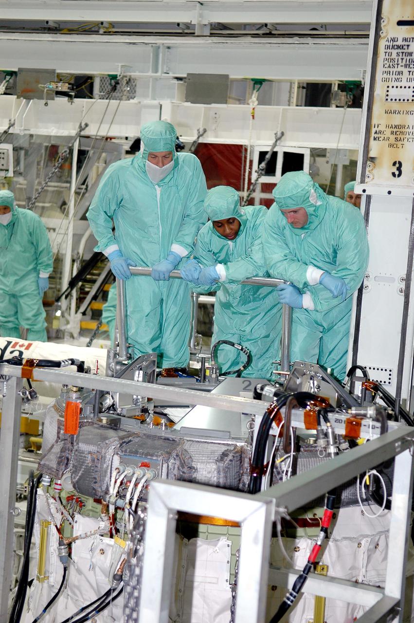 KENNEDY SPACE CENTER, FLA. - In the Orbiter Processing Facility at NASA’s Kennedy Space Center, astronauts of the second Return to Flight mission, STS-121, look over hardware in Atlantis' payload bay. From left are United Space Alliance trainer Steve Kieffer, Mission Specialist Stephanie D. Wilson and Pilot Mark E. Kelly. The crew is at KSC to participate in the Crew Equipment Interface Test (CEIT). During CEIT, the crew has an opportunity to get a hands-on look at the orbiter and equipment they will be working with on their missions. Mission STS-121 is scheduled to launch aboard Atlantis in July.