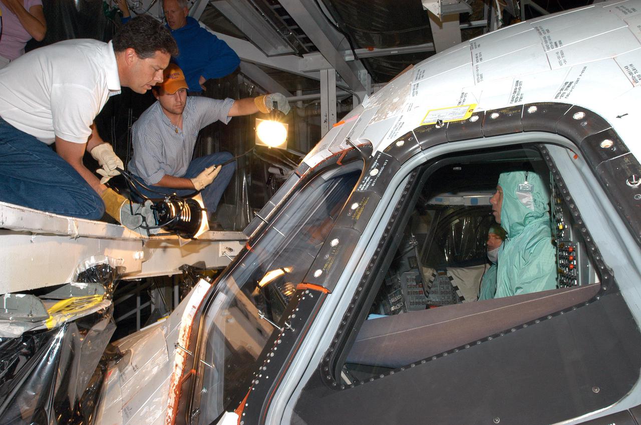 KENNEDY SPACE CENTER, FLA.  -  In Orbiter Processing Facility bay 1, United Space Alliance technicians help STS-121 Mission Commander Steven W. Lindsey (right) and Pilot Mark E. Kelly with an inspection of the windows in Atlantis' cockpit. The STS-121 crew is at KSC to participate in the Crew Equipment Interface Test (CEIT). During CEIT, the crew has an opportunity to get a hands-on look at the orbiter and equipment they will be working with on their mission. STS-121, the second Return to Flight mission, is scheduled to launch aboard Atlantis in July.
