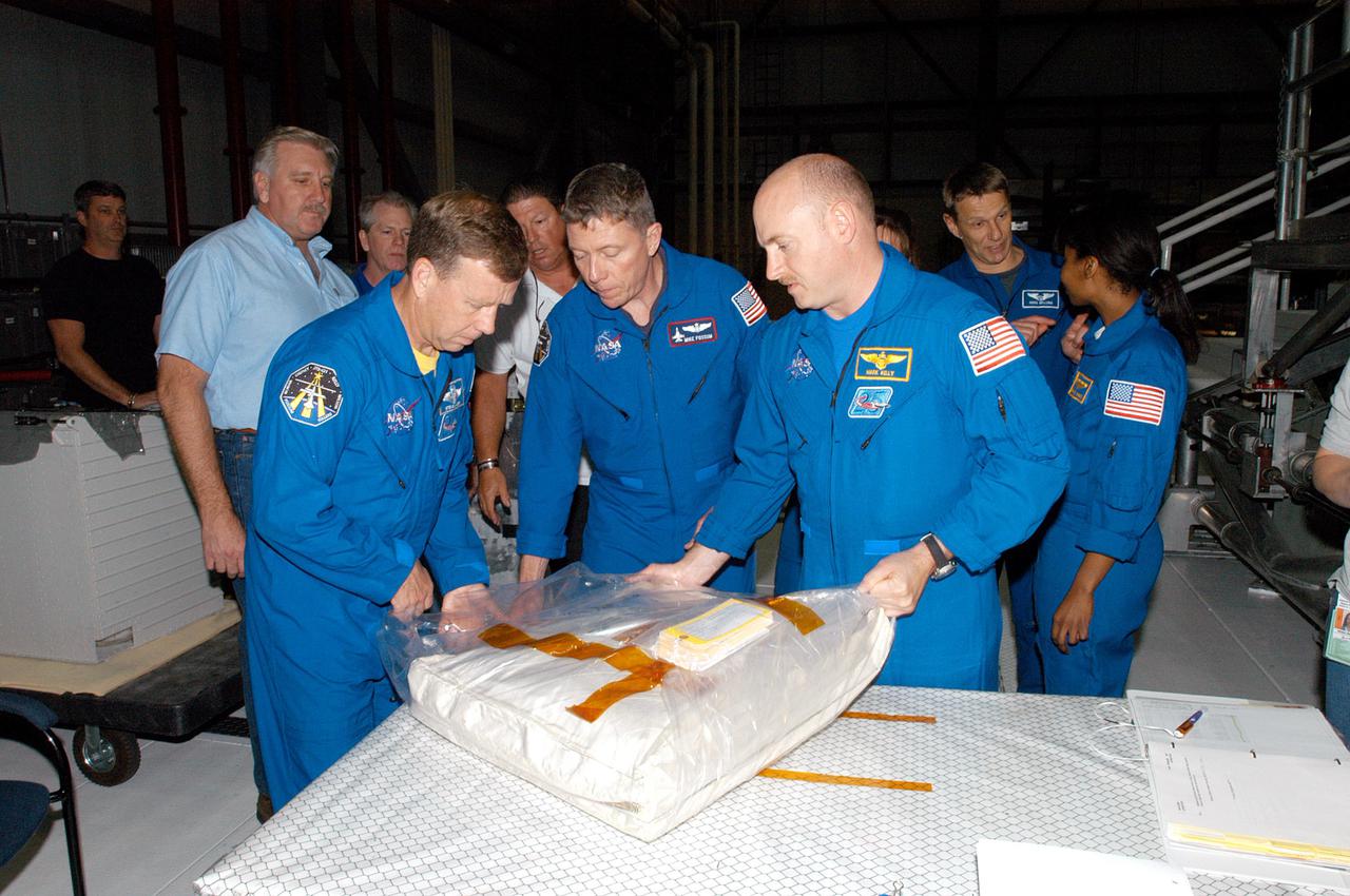KENNEDY SPACE CENTER, FLA. - During Crew Equipment Interface Test (CEIT) at NASA’s Kennedy Space Center, STS-121 crew members are opening Window Shade bag for review. From left are Commander Steven W. Lindsey, Mission Specialist Michael E. Fossum and Pilot Mark E. Kelly. Behind them, at right, are Mission Specialists Piers J. Sellers and Stephanie Wilson. STS-121 is the second Return to Flight mission to the International Space Station. During CEIT, the crew has an opportunity to get a hands-on look at the orbiter and equipment they will be working with on their mission. Mission STS-121 is scheduled to launch aboard Space Shuttle Atlantis in July.