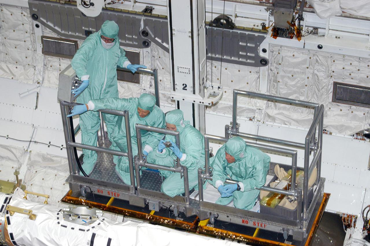 KENNEDY SPACE CENTER, FLA. - In Orbiter Processing Facility bay 1, astronauts of the second Return to Flight mission, STS-121, and United Space Alliance technicians look over the Orbital Boom Sensor System (OBSS) in Atlantis' payload bay. In the railed enclosure are, from left, the United Space Alliance (USA) bucket operator, Mission Specialist Piers J. Sellers, a USA trainer, and Mission Specialist Michael E. Fossum. The 50-foot-long OBSS is attached to the Remote Manipulator System, or Shuttle robotic arm, and is one of the new safety measures for Return to Flight, equipping the orbiter with cameras and laser systems to inspect the Shuttle’s Thermal Protection System while in space. The STS-121 crew is at KSC to participate in the Crew Equipment Interface Test (CEIT). During CEIT, the crew has an opportunity to get a hands-on look at the orbiter and equipment they will be working with on their mission. STS-121, the second Return to Flight mission, is scheduled to launch aboard Atlantis in July.