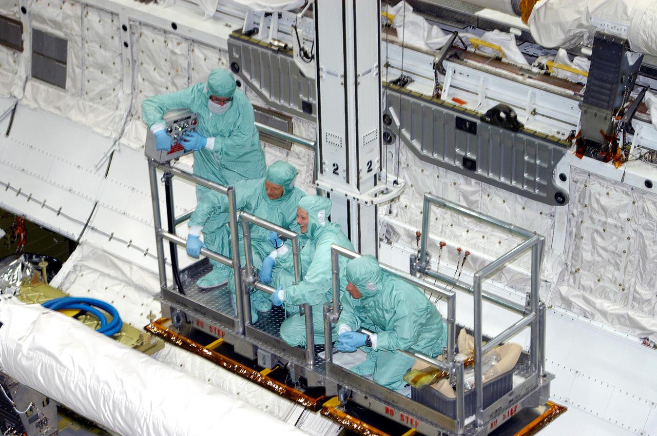 KENNEDY SPACE CENTER, FLA. - In Orbiter Processing Facility bay 1, astronauts of the second Return to Flight mission, STS-121, and United Space Alliance technicians look over the Orbital Boom Sensor System (OBSS) in Atlantis' payload bay. In the railed enclosure are, from left, the United Space Alliance (USA) bucket operator, Mission Specialist Piers J. Sellers, a USA trainer, and Mission Specialist Michael E. Fossum. The 50-foot-long OBSS is attached to the Remote Manipulator System, or Shuttle robotic arm, and is one of the new safety measures for Return to Flight, equipping the orbiter with cameras and laser systems to inspect the Shuttle’s Thermal Protection System while in space. The STS-121 crew is at KSC to participate in the Crew Equipment Interface Test (CEIT). During CEIT, the crew has an opportunity to get a hands-on look at the orbiter and equipment they will be working with on their mission. STS-121, the second Return to Flight mission, is scheduled to launch aboard Atlantis in July.
