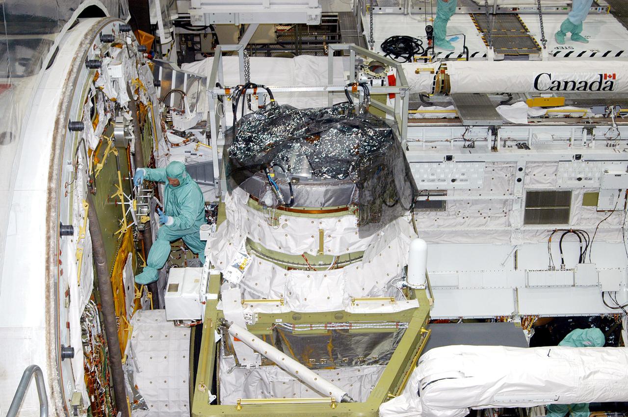 KENNEDY SPACE CENTER, FLA. - During Crew Equipment Interface Test (CEIT) in the Orbiter Processing Facility at NASA’s Kennedy Space Center, STS-121 Mission Specialist Michael E. Fossum familiarizes himself with the Portable Foot Restraint on the forward bulkhead of Atlantis. The Airlock is in the center.  During CEIT, the crew has an opportunity to get a hands-on look at the orbiter and equipment they will be working with on their mission. Mission STS-121 is scheduled to launch aboard Space Shuttle Atlantis in July.