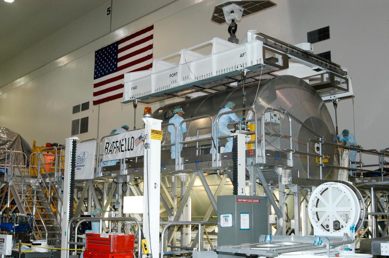 KENNEDY SPACE CENTER, FLA. - In the Space Station Processing Facility, workers attach an overhead crane to the Multi-Purpose Logistics Module Raffaello, which is being moved to the Payload Transportation Canister for installation and transfer to Launch Pad 39-B.  Raffaello will travel aboard Space Shuttle Discovery on Return to Flight Mission STS-114 to the International Space Station.  Raffaello will carry 12 racks of cargo to the Station, including food, clothing, spare parts and research equipment.  The Boeing Company,  a KSC and NASA prime contractor for ISS element processing, prepared Raffaello for flight.  The module was built by the Italian Space Agency for NASA under a cooperative space agreement.