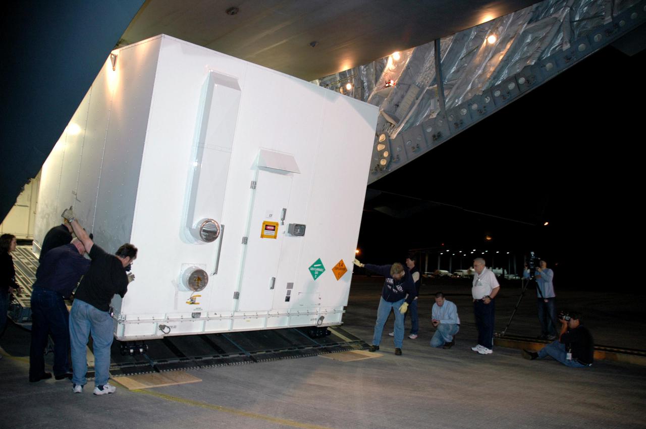 KENNEDY SPACE CENTER, FLA. - Workers at Kennedy Space Center's Shuttle Landing Facility roll one of two containers with the Mars Reconnaissance Orbiter (MRO) equipment away from the Air Force C-17 cargo plane that delivered it. The MRO is being moved to the Payload Hazardous Servicing Facility. The MRO was built by Lockheed Martin for NASA's Jet Propulsion Laboratory in California. It is the next major step in Mars exploration and scheduled for launch from Cape Canaveral Air Force Station in a window opening Aug. 10. The MRO carries six primary instruments: the High Resolution Imaging Science Experiment, Context Camera, Mars Color Imager, Compact Reconnaissance Imaging Spectrometer for Mars, Mars Climate Sounder and Shallow Radar. By 2007, the MRO will begin a series of global mapping, regional survey and targeted observations from a near-polar, low-altitude Mars orbit. It will observe the atmosphere and surface of Mars while probing its shallow subsurface as part of a “follow the water” strategy.