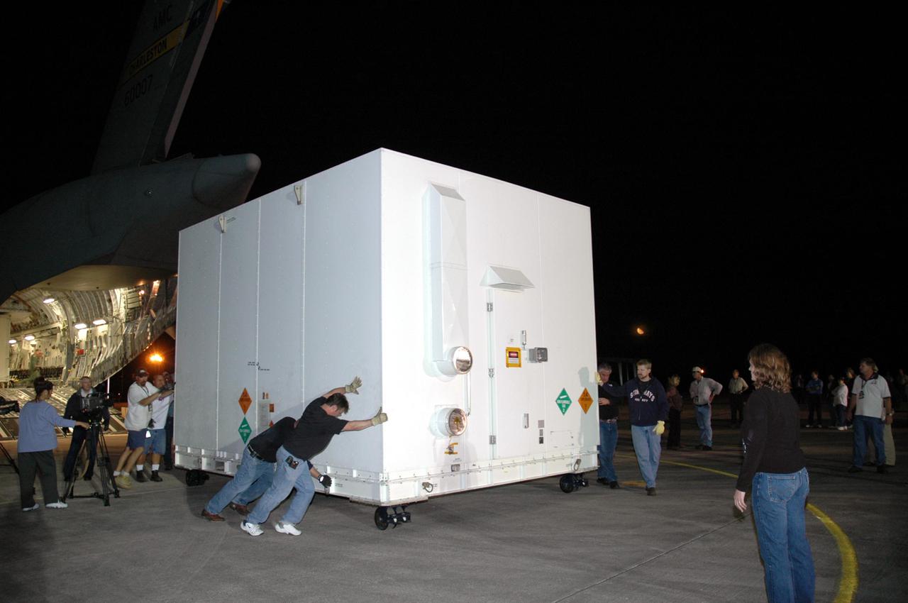 KENNEDY SPACE CENTER, FLA. - Workers at Kennedy Space Center's Shuttle Landing Facility roll one of two containers with the Mars Reconnaissance Orbiter (MRO) equipment away from the Air Force C-17 cargo plane that delivered it. The MRO is being moved to the Payload Hazardous Servicing Facility. The MRO was built by Lockheed Martin for NASA’s Jet Propulsion Laboratory in California. It is the next major step in Mars exploration and scheduled for launch from Cape Canaveral Air Force Station in a window opening Aug. 10. The MRO carries six primary instruments: the High Resolution Imaging Science Experiment, Context Camera, Mars Color Imager, Compact Reconnaissance Imaging Spectrometer for Mars, Mars Climate Sounder and Shallow Radar. By 2007, the MRO will begin a series of global mapping, regional survey and targeted observations from a near-polar, low-altitude Mars orbit. It will observe the atmosphere and surface of Mars while probing its shallow subsurface as part of a “follow the water” strategy.