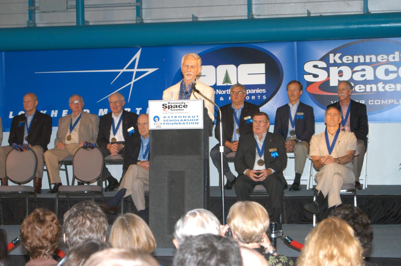 KENNEDY SPACE CENTER, FLA. -  Owen Garriott, chairman of the Astronaut Hall of Fame, speaks to guests at the Induction Ceremony of three new additions to the Hall of Fame: Gordon Fullerton, Bruce McCandless and Joe Allen.  Seated on stage are current Hall of Famers, from left in the back row, Charles Duke, Jack Lousma, Bill Pogue, Dan Brandenstein, Robert “Hoot” Gibson and Stephen Covey; in front row, Jim Lovell, Fred Haise and Vance Brand. Recognized for their individual flight accomplishments and contributions to the success and future success of the U.S. space program, this elite group of inductees is among only 60 astronauts to be honored in the Hall of Fame and the fourth group of Space Shuttle astronauts named.