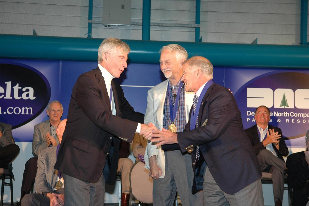 KENNEDY SPACE CENTER, FLA. -  At the Astronaut Hall of Fame Induction Ceremony, Hall of Famer John Young (left) congratulates new inductee Joe Allen.  Between them is Owen Garriott, chairman of the Astronaut Hall of Fame.  Current Hall of Famers seen behind them are Al Worden (left) and Robert Crippen (right).  The other new inductees are Bruce McCandless and Gordon Fullerton.  The event is being held in the Kennedy Space Center Visitor Complex’s Apollo_Saturn V Center. Recognized for their individual flight accomplishments and contributions to the success and future success of the U.S. space program, this elite group of inductees is among only 60 astronauts to be honored in the Hall of Fame and the fourth group of Space Shuttle astronauts named.