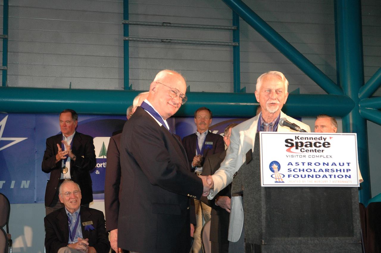 KENNEDY SPACE CENTER, FLA. -  At the Astronaut Hall of Fame Induction Ceremony, new inductee Bruce McCandless (left) is congratulated by Chairman Owen Garriott.  Seen behind them are current Hall of Famers (on left) Robert Crippen (standing) and Jim Lovell and (center) Robert “Hoot” Gibson.  The other new inductees are Joe Allen and Gordon Fullerton. The event is being held in the Kennedy Space Center Visitor Complex’s Apollo_Saturn V Center.  Recognized for their individual flight accomplishments and contributions to the success and future success of the U.S. space program, this elite group of inductees is among only 60 astronauts to be honored in the Hall of Fame and the fourth group of Space Shuttle astronauts named.