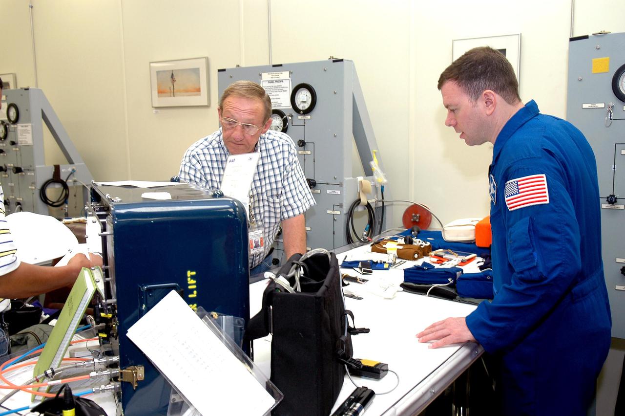 KENNEDY SPACE CENTER, FLA. - As part of pre-pack and fit check for Terminal Countdown Demonstration Test (TCDT) activities, STS-114 Pilot Jim Kelly looks at equipment that will be on the flight. The TCDT is held at KSC prior to each Space Shuttle flight. It provides the crew of each mission an opportunity to participate in simulated countdown activities. The test ends with a mock launch countdown culminating in a simulated main engine cutoff. The crew also spends time undergoing emergency egress training exercises at the launch pad. STS-114 is the first Return to Flight mission to the International Space Station. The launch window extends July 13 through July 31.