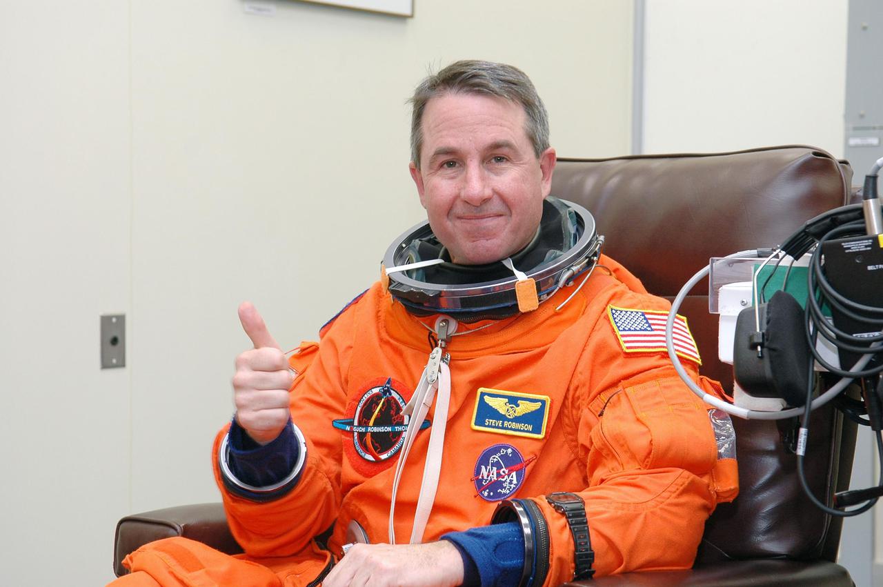 KENNEDY SPACE CENTER, FLA. - As part of pre-pack and fit check for Terminal Countdown Demonstration Test (TCDT) activities, STS-114 Mission Specialist Stephen Robinson signals okay for his launch suit check. The TCDT is held at KSC prior to each Space Shuttle flight. It provides the crew of each mission an opportunity to participate in simulated countdown activities. The test ends with a mock launch countdown culminating in a simulated main engine cutoff. The crew also spends time undergoing emergency egress training exercises at the launch pad. STS-114 is the first Return to Flight mission to the International Space Station. The launch window extends July 13 through July 31.