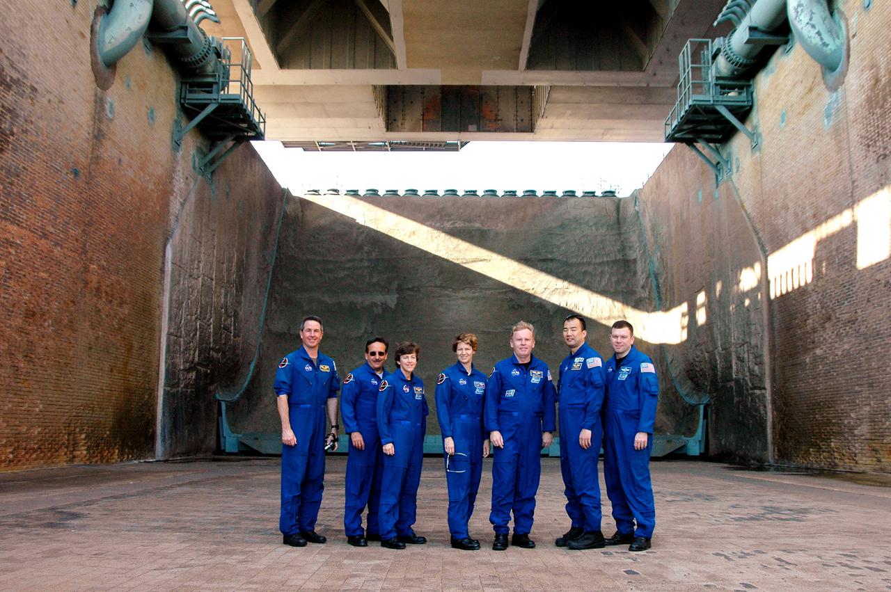 KENNEDY SPACE CENTER, FLA. -    During a walkdown of Launch Pad 39B, the STS-114 crew pauses for a photograph in the flame trench underneath the pad.  The flame trench, built with concrete and refractory brick, bisects the pad at ground level.  It is 490 feet long, 58 feet wide and 42 feet deep. The flame deflector system includes an inverted, V-shaped steel structure covered with a high-temperature concrete material five inches thick that extends across the center of the flame trench.  One side of the “V” receives and deflects the flames from the Orbiter main engines; the opposite side deflects the flames from the Solid Rocket Boosters. There are also two movable deflectors at the top of the trench to provide additional protection to Shuttle hardware from the Solid Rocket Booster flames.  STS-114 is designated the first Return to Flight mission, with a launch window extending from July 13 to July 31. The crew is at KSC for Terminal Countdown Demonstration Test (TCDT) activities.  The TCDT is held at KSC prior to each Space Shuttle flight. It provides the crew of each mission an opportunity to participate in simulated countdown activities. The test ends with a mock launch countdown culminating in a simulated main engine cutoff. The crew also spends time undergoing emergency egress training exercises at the launch pad.