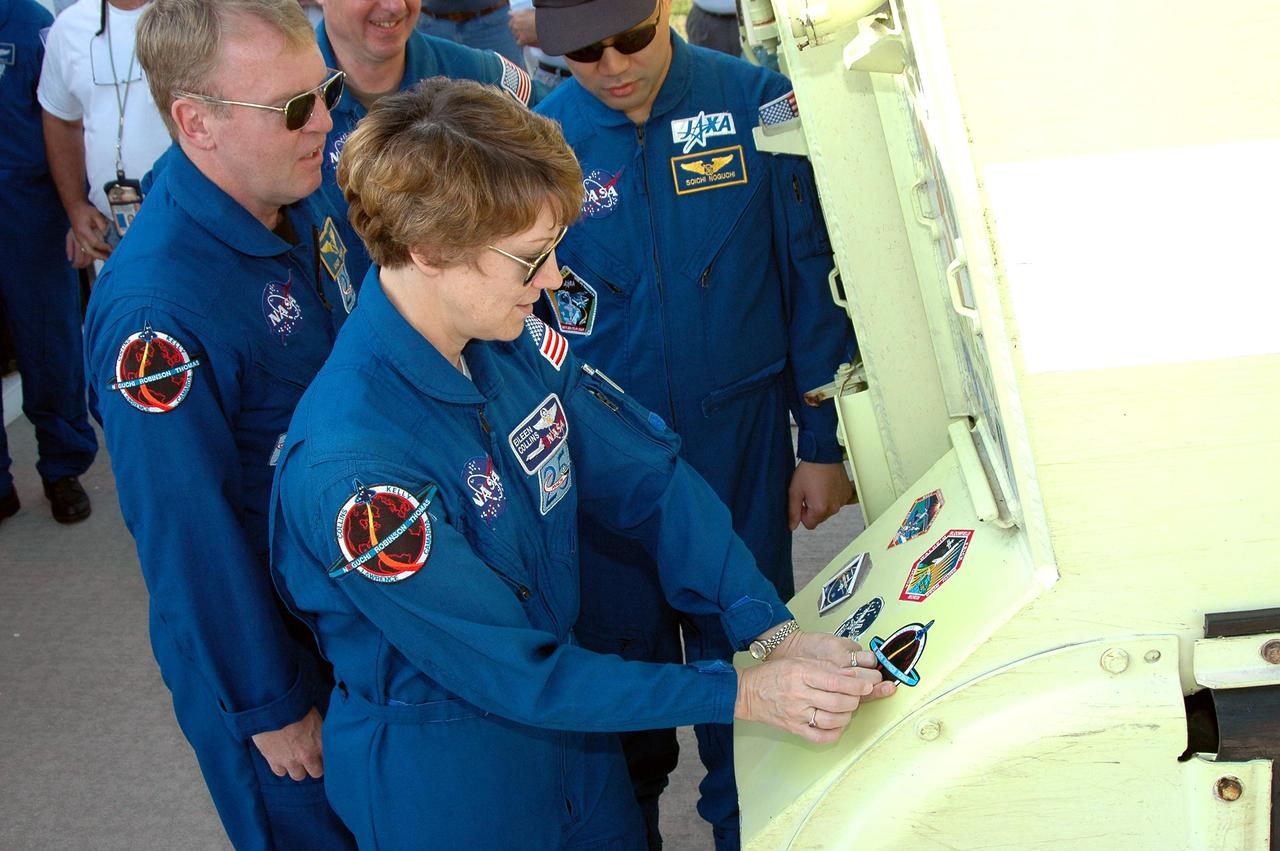 KENNEDY SPACE CENTER, FLA. - STS-114 Commander Eileen Collins places a mission patch on an M-113 armored personnel carrier during Terminal Countdown Demonstration Test (TCDT) activities. Looking on are Mission Specialists Andrew Thomas, Stephen Robinson and Soichi Noguchi, who is with the Japan Aerospace Exploration Agency.. The crew is at KSC for Terminal Countdown Demonstration Test (TCDT) activities. The TCDT is held at KSC prior to each Space Shuttle flight. It provides the crew of each mission an opportunity to participate in simulated countdown activities. The test ends with a mock launch countdown culminating in a simulated main engine cutoff. The crew also spends time undergoing emergency egress training exercises at the launch pad. STS-114 is designated the first Return to Flight mission, with a launch window extending from July 13 to July 31.