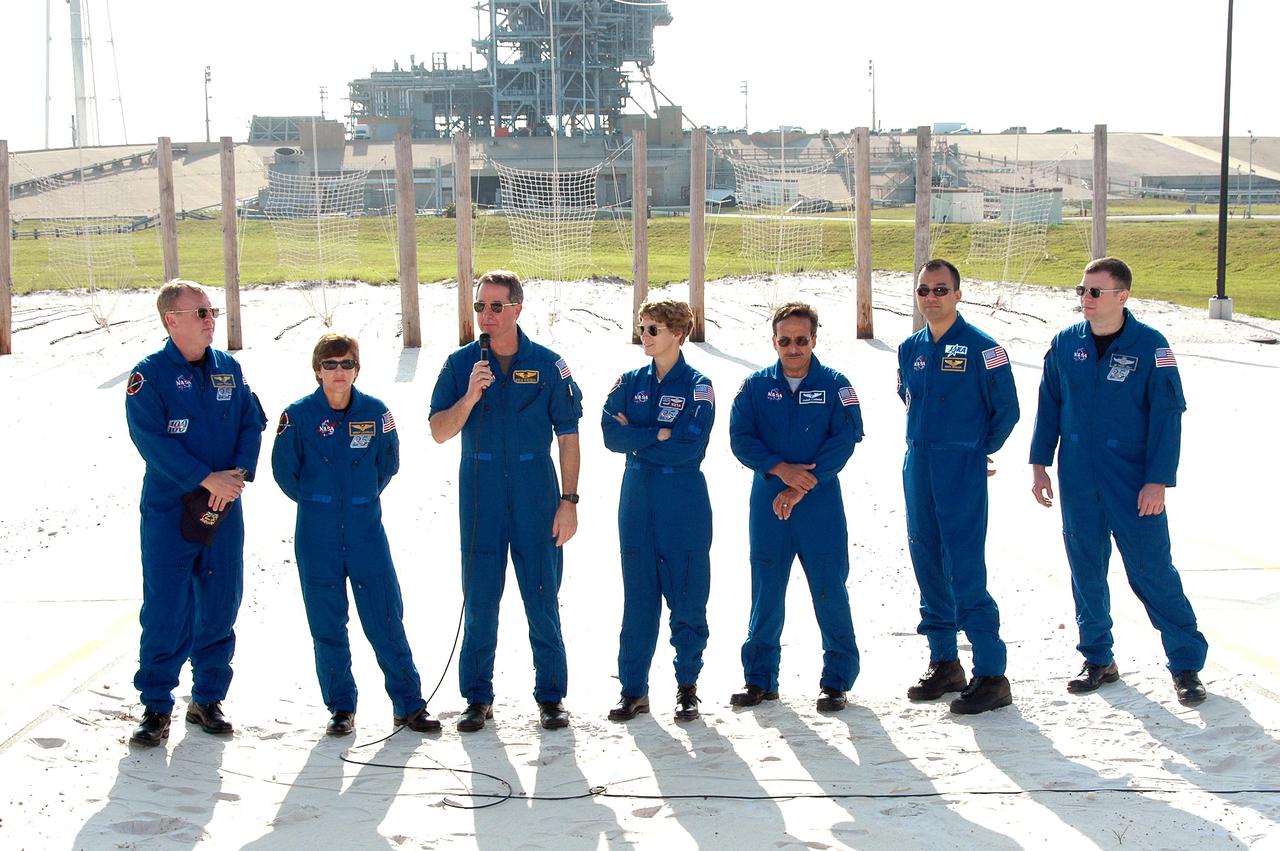 KENNEDY SPACE CENTER, FLA. - The STS-114 crew gathers for media questions at the slidewire basket landing area on Launch Pad 39B. Mission Specialist Stephen Robinson has the microphone. The other crew members are, from left, Mission Specialists Andrew Thomas and Wendy Lawrence, Commander Eileen Collins, Mission Specialists Charles Camarda and Soichi Noguchi, and Pilot James Kelly. Noguchi is with the Japan Aerospace Exploration Agency. The TCDT is held at KSC prior to each Space Shuttle flight. It provides the crew of each mission an opportunity to participate in simulated countdown activities. The test ends with a mock launch countdown culminating in a simulated main engine cutoff. The crew also spends time undergoing emergency egress training exercises at the launch pad. STS-114 is designated the first Return to Flight mission, with a launch window extending from July 13 to July 31.