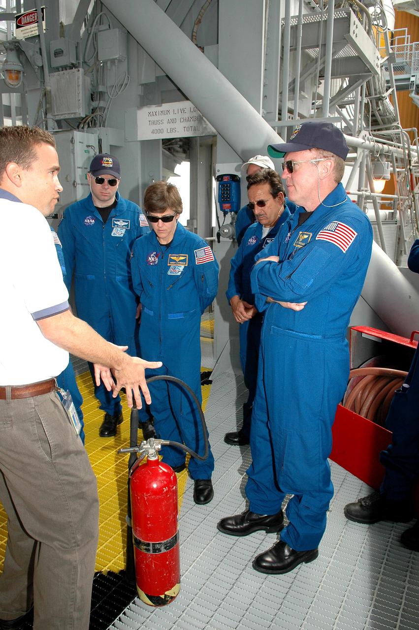 KENNEDY SPACE CENTER, FLA. - On the Fixed Service Structure at Launch Pad 39B, the STS-114 crew gets instructions about fire extinguisher use. The astronauts seen here are (from left) Pilot James Kelly, Commander Eileen Collins, and Mission Specialists Charles Camarda and Andrew Thomas. The training is part of Terminal Countdown Demonstration Test activities. The TCDT is held at KSC prior to each Space Shuttle flight. It provides the crew of each mission an opportunity to participate in simulated countdown activities. The test ends with a mock launch countdown culminating in a simulated main engine cutoff. The crew also spends time undergoing emergency egress training exercises at the launch pad. STS-114 is designated the first Return to Flight mission, with a launch window extending from July 13 to July 31.