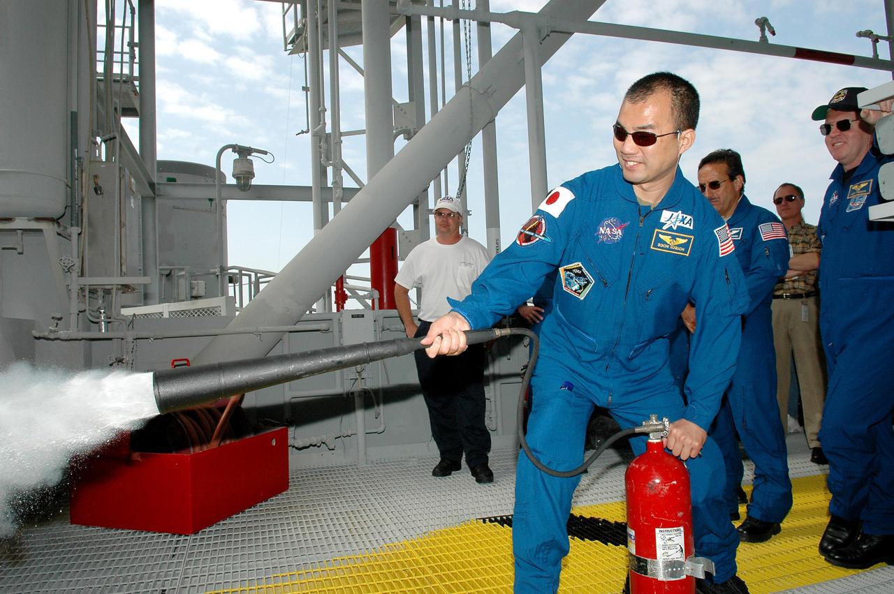 KENNEDY SPACE CENTER, FLA. - On the Fixed Service Structure at Launch Pad 39B, STS-114 Mission Specialist Soichi Noguchi practices using a fire extinguisher. Noguchi is with the Japan Aerospace Exploration Agency. The training is part of Terminal Countdown Demonstration Test activities. Other crew members looking on, behind Noguchi, are Mission Specialists Charles Camarda and Andrew Thomas. The TCDT is held at KSC prior to each Space Shuttle flight. It provides the crew of each mission an opportunity to participate in simulated countdown activities. The test ends with a mock launch countdown culminating in a simulated main engine cutoff. The crew also spends time undergoing emergency egress training exercises at the launch pad. STS-114 is designated the first Return to Flight mission, with a launch window extending from July 13 to July 31.