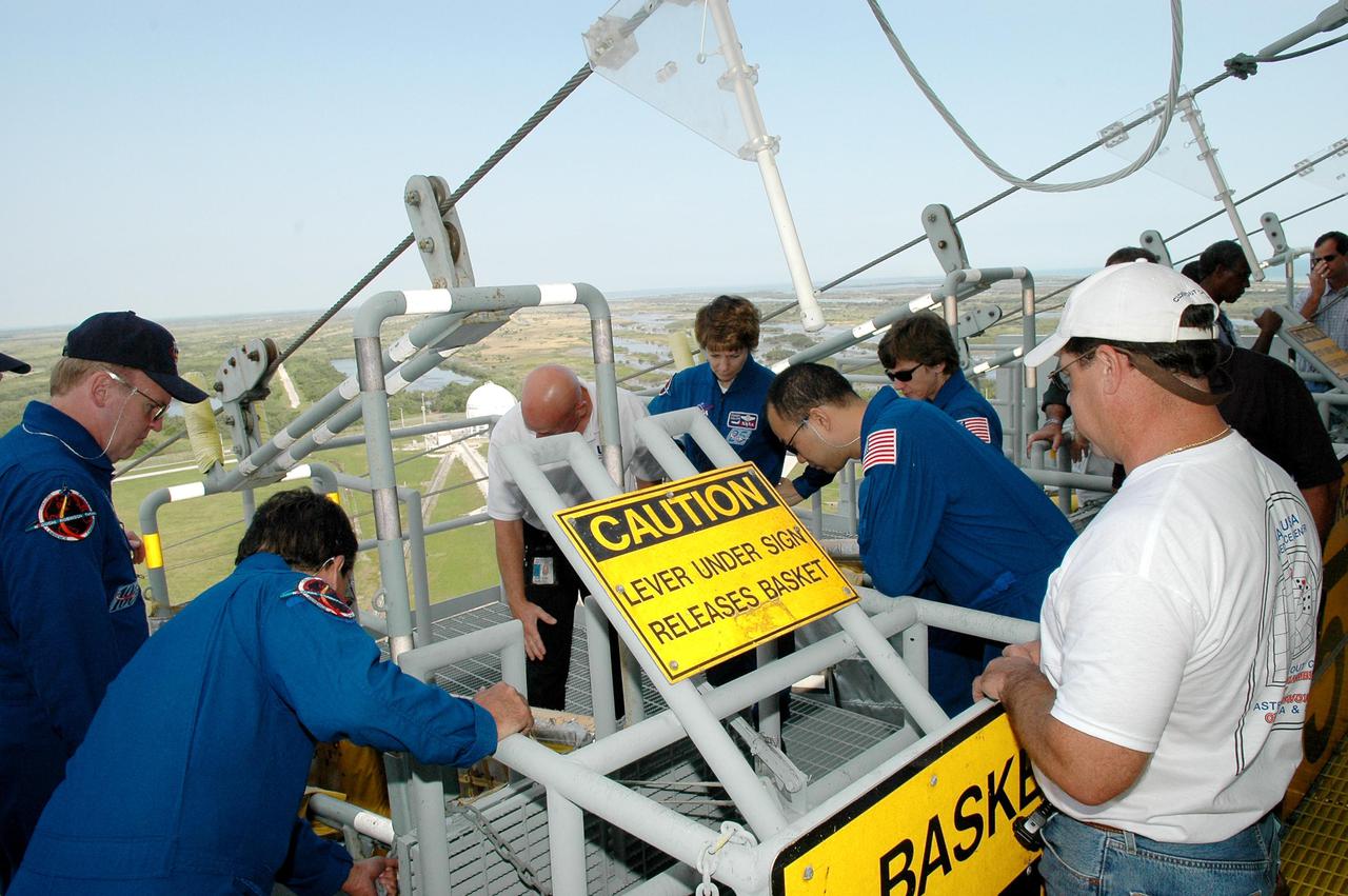 KENNEDY SPACE CENTER, FLA. -  On the Fixed Service Structure at Launch Pad 39B, the STS-114 crew gets instructions on using the slidewire basket, emergency egress equipment from the pad.  Crew members seen here are (from left) Mission Specialists Andrew Thomas and Charles Camarda, Commander Eileen Collins, and Mission Specialists Soichi Noguchi and Wendy Lawrence.  Noguchi is with the Japan Aerospace Exploration Agency.  The training is part of Terminal Countdown Demonstration Test activities.  The TCDT is held at KSC prior to each Space Shuttle flight. It provides the crew of each mission an opportunity to participate in simulated countdown activities. The test ends with a mock launch countdown culminating in a simulated main engine cutoff. The crew also spends time undergoing emergency egress training exercises at the launch pad.  STS-114 is designated the first Return to Flight mission, with a launch window extending from July 13 to July 31.