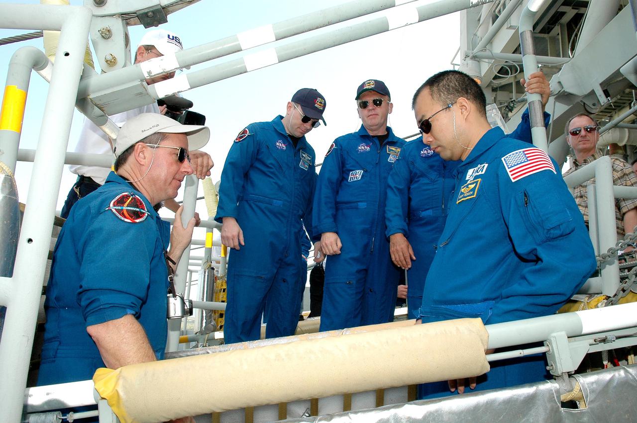 KENNEDY SPACE CENTER, FLA. - On the Fixed Service Structure at Launch Pad 39B, STS-114 Mission Specialists Stephen Robinson (left) and Soichi Noguchi (right) have climbed into the slidewire basket, emergency egress equipment from the pad. Watching them (in center) are Pilot James Kelly and Mission Specialist Andrew Thomas. Noguchi is with the Japan Aerospace Exploration Agency. The training is part of Terminal Countdown Demonstration Test activities. The TCDT is held at KSC prior to each Space Shuttle flight. It provides the crew of each mission an opportunity to participate in simulated countdown activities. The test ends with a mock launch countdown culminating in a simulated main engine cutoff. The crew also spends time undergoing emergency egress training exercises at the launch pad. STS-114 is designated the first Return to Flight mission, with a launch window extending from July 13 to July 31.