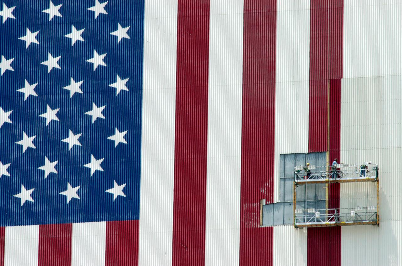 KENNEDY SPACE CENTER, FLA. -  About 450 feet above the ground, painters on scaffolding begin preparations  to repaint portions of the American flag on the side of the Vehicle Assembly Building at NASA’s Kennedy Space Center.  The flag was damaged in the hurricanes of 2004 that assaulted the east coast of Florida.  Winds pulled a number of panels from the side of the 525-foot-high building.   The flag is 209 feet by 110 feet. Each star is more than six feet in diameter and each stripe is nine feet wide.