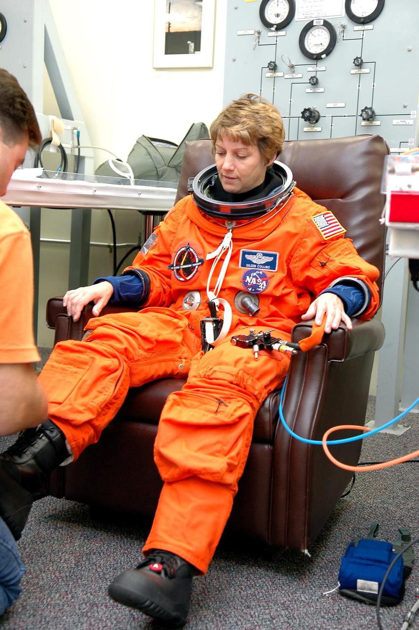 KENNEDY SPACE CENTER, FLA. - A suit technician helps STS-114 Commander Eileen Collins with a boot as she suits up in the Operations and Checkout Building for the trip to Launch Pad 39B for a mock launch countdown culminating in a simulated main engine cutoff.  The dress rehearsal is part of Terminal Countdown Demonstration Test (TCDT) activities held prior to each Space Shuttle flight. It provides the crew of each mission an opportunity to participate in various simulated countdown activities, including equipment familiarization and emergency egress training. STS-114 is the first Return to Flight mission to the International Space Station.  The launch window extends July 13 through July 31.