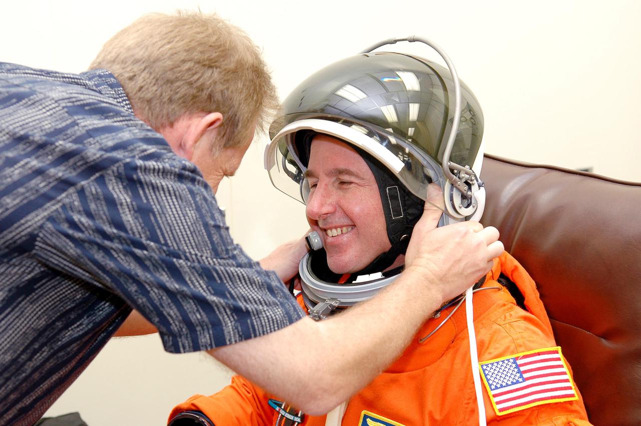 KENNEDY SPACE CENTER, FLA. - A suit technician helps STS-114 Mission Specialist Stephen Robinson suit up in the Operations and Checkout Building for the trip to Launch Pad 39B for a mock launch countdown culminating in a simulated main engine cutoff.  The dress rehearsal is part of Terminal Countdown Demonstration Test (TCDT) activities held prior to each Space Shuttle flight. It provides the crew of each mission an opportunity to participate in various simulated countdown activities, including equipment familiarization and emergency egress training. STS-114 is the first Return to Flight mission to the International Space Station.  The launch window extends July 13 through July 31.