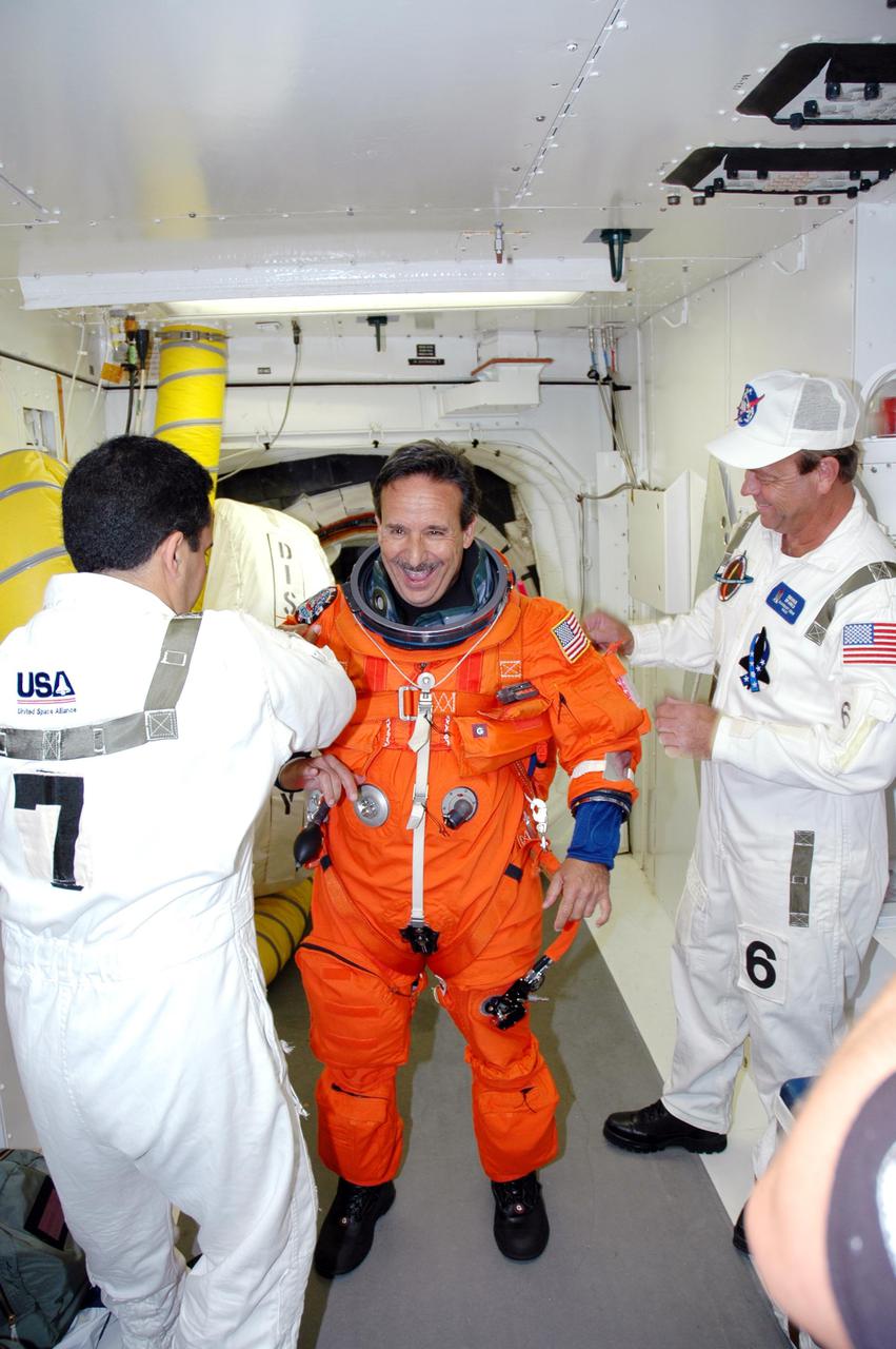 KENNEDY SPACE CENTER, FLA. -With the help of the Closeout Crew in the White Room on Launch Pad 39B, STS-114 Mission Specialist Charles Camarda adjusts his launch suit before entering Space Shuttle Discovery. The crew is taking part in a full dress rehearsal for launch, including countdown and culminating in main engine cutoff. The rehearsal is the final part of Terminal Countdown Demonstration Test (TCDT) activities that the crew has been involved in for three days. TCDT provides the crew of each mission an opportunity to participate in various simulated countdown activities, including equipment familiarization and emergency egress training. STS-114 is the first Return to Flight mission to the International Space Station. The launch window extends July 13 through July 31.