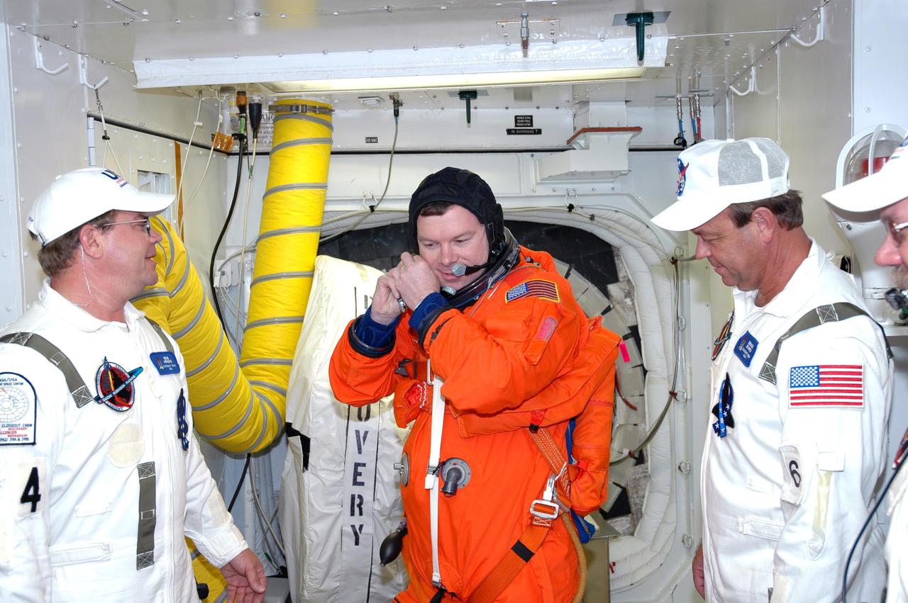 KENNEDY SPACE CENTER, FLA. - With the Closeout Crew looking on in the White Room on Launch Pad 39B, STS-114 Pilot James Kelly makes adjustments to his launch suit before entering Space Shuttle Discovery. The crew is taking part in a full dress rehearsal for launch, including countdown and culminating in main engine cutoff. The rehearsal is the final part of Terminal Countdown Demonstration Test (TCDT) activities that the crew has been involved in for three days. TCDT provides the crew of each mission an opportunity to participate in various simulated countdown activities, including equipment familiarization and emergency egress training. STS-114 is the first Return to Flight mission to the International Space Station. The launch window extends July 13 through July 31.