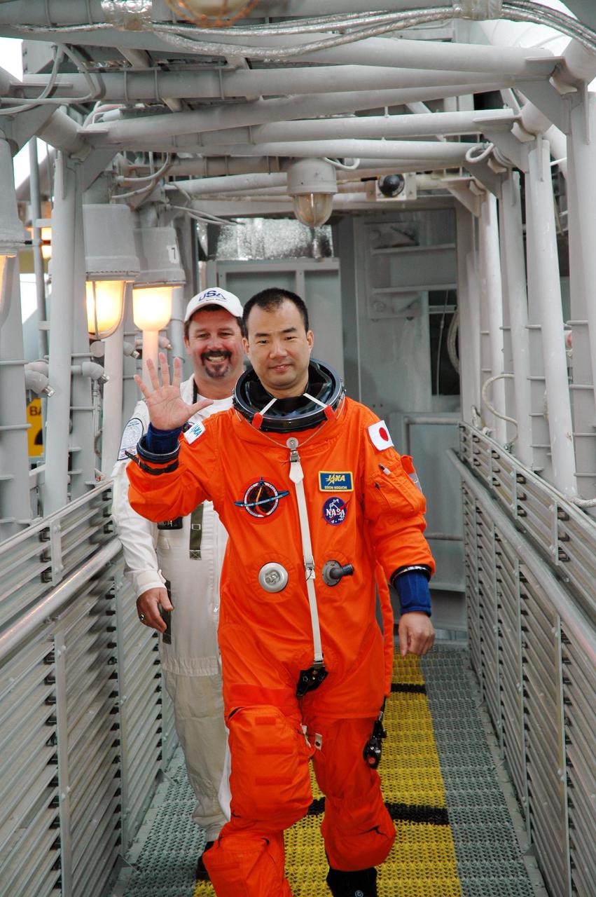 KENNEDY SPACE CENTER, FLA. - With a member of the Closeout Crew following behind, STS-114 Mission Specialist Soichi Noguchi heads for the White Room on Launch Pad 39B, where he will complete adjustments to his launch suit before entering Space Shuttle Discovery. Noguchi is with the Japan Aerospace Exploration Agency. The crew is taking part in a full dress rehearsal for launch, including countdown and culminating in main engine cutoff. The rehearsal is the final part of Terminal Countdown Demonstration Test (TCDT) activities that the crew has been involved in for three days. TCDT provides the crew of each mission an opportunity to participate in various simulated countdown activities, including equipment familiarization and emergency egress training. STS-114 is the first Return to Flight mission to the International Space Station. The launch window extends July 13 through July 31.
