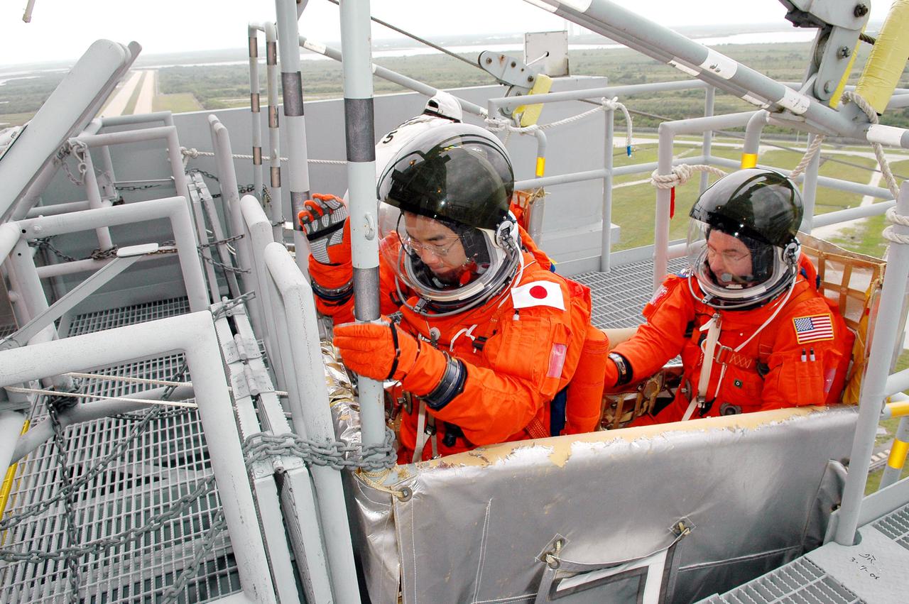 KENNEDY SPACE CENTER, FLA. -  Following the mock countdown on Launch Pad 39B, STS-114 Mission Specialists Soichi Noguchi (left) and Stephen Robinson climb into a slidewire basket used for emergency egress from the Fixed Service Structure at the pad.  This is part of the pre-launch training included in Terminal Countdown Demonstration Test (TCDT) activities.   TCDT provides the crew of each mission an opportunity to participate in various simulated countdown activities, including equipment familiarization and emergency egress training. STS-114 is the first Return to Flight mission to the International Space Station. The launch window extends July 13 through July 31.