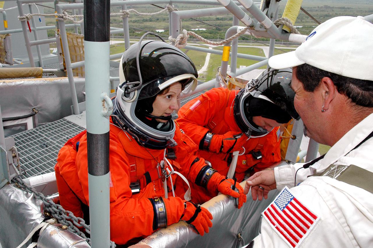 KENNEDY SPACE CENTER, FLA. -  Following the mock countdown on Launch Pad 39B, STS-114 Commander Eileen Collins (left) climbs into a slidewire basket used for emergency egress from the Fixed Service Structure at the pad.  This is part of the pre-launch training included in Terminal Countdown Demonstration Test (TCDT) activities.  TCDT provides the crew of each mission an opportunity to participate in various simulated countdown activities, including equipment familiarization and emergency egress training. STS-114 is the first Return to Flight mission to the International Space Station. The launch window extends July 13 through July 31.