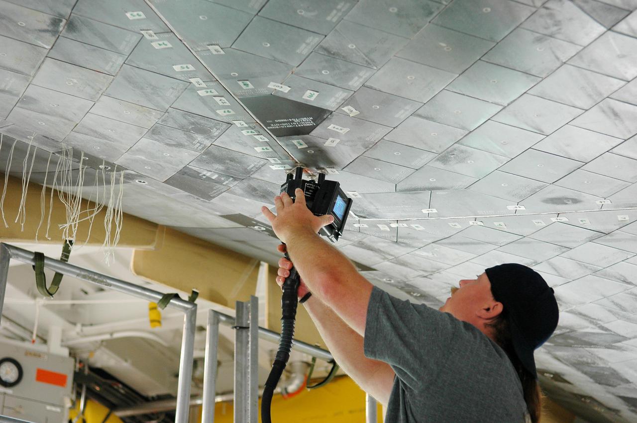 KENNEDY SPACE CENTER, FLA. - In Orbiter Processing Facility bay 1 at NASA’s Kennedy Space Center, United Space Alliance technician Butch Lato uses a laser tool to take step and gap measurements on Thermal Protection System tiles on the underside of orbiter Atlantis. Other processing continues on Atlantis for its mission, designated STS-121, to the International Space Station. The launch planning window is Sept. 9 - 24.