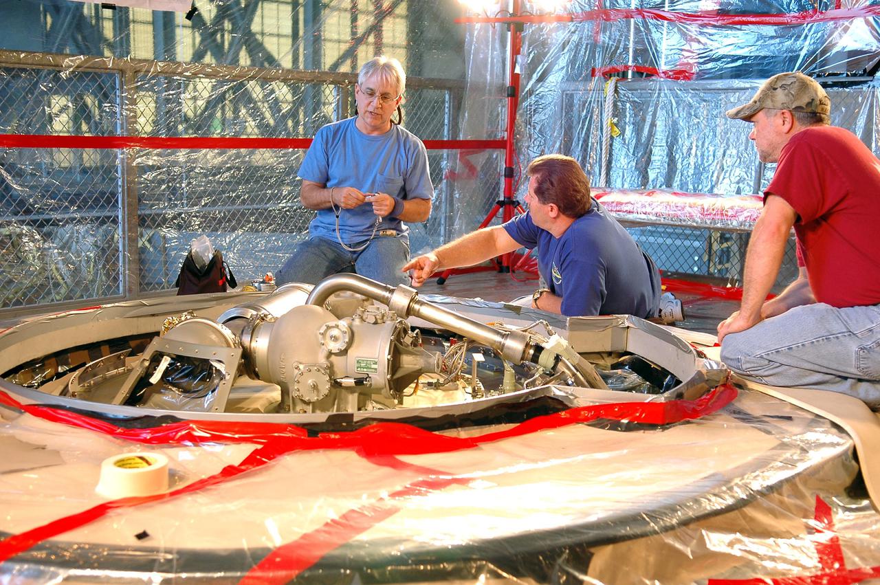 KENNEDY SPACE CENTER, FLA. - In the Vehicle Assembly Building, Michael Cinquigianno (left), who is a system test mechanical technician with Lockheed Martin, checks out the vent valve assembly on External Tank 121. Next to him is Lance Mercier, with Lockheed Martin Quality Control. The assembly sits on top of the tank and, when on the launch pad, is connected to the “beanie cap,” a swing-arm-mounted cap that covers the oxygen tank vent on top of the tank during the countdown. The cap is retracted about two minutes before liftoff. The cap siphons off oxygen vapor that threatens to form large ice on the tank, thus protecting the orbiter’s thermal protection system during launch. The External Tanks are built by Lockheed Martin at the Michoud Assembly Facility near New Orleans. The tank is being prepared to fly with Discovery on mission STS-114, whose launch window extends July 13 to July 31.
